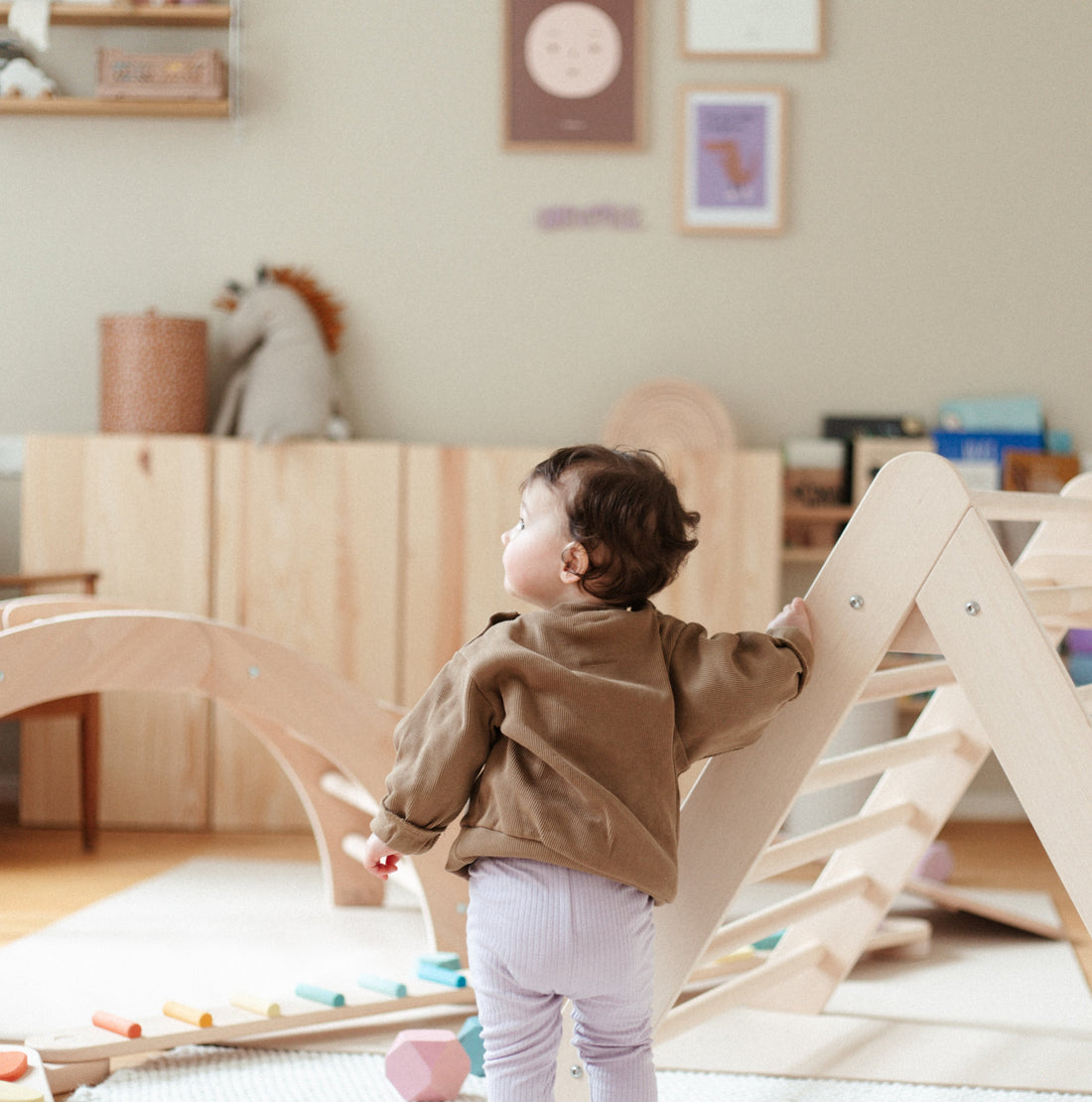 Kind steht in Kinderzimmer neben Kletterdreieck.