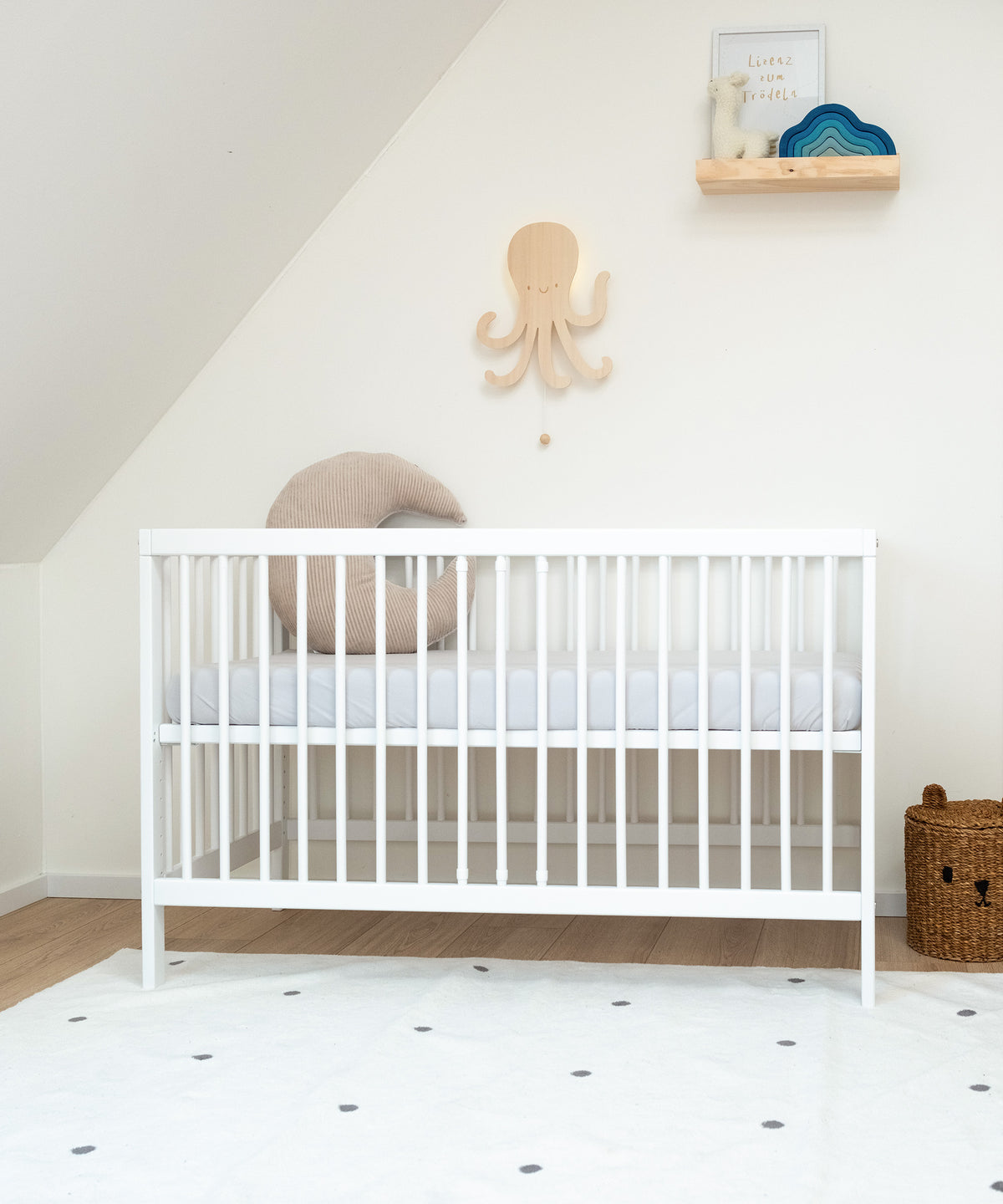Babybett weiß mit hoch gestellter Liegefläche in Kinderzimmer.