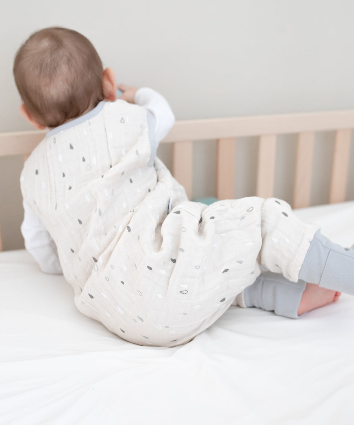 Baby mit Musselin Sommerschlafsack in Bett.