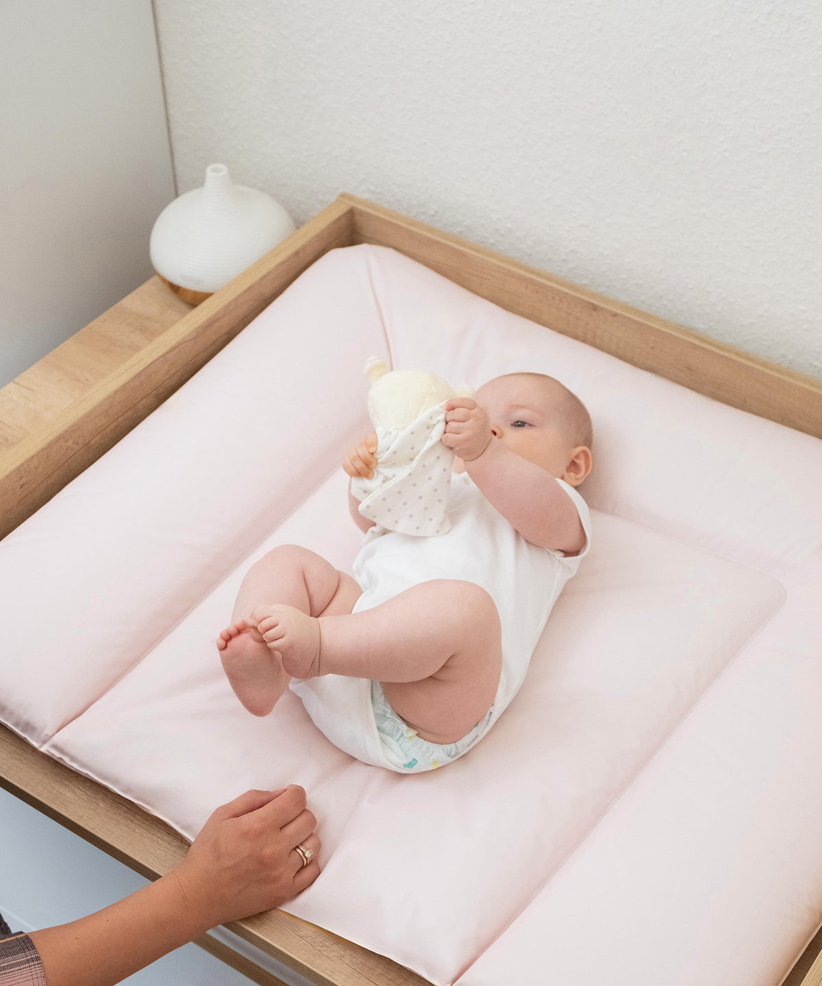 Baby liegt auf abwaschbarer Wickelunterlage 72x85 cm in Rosé.