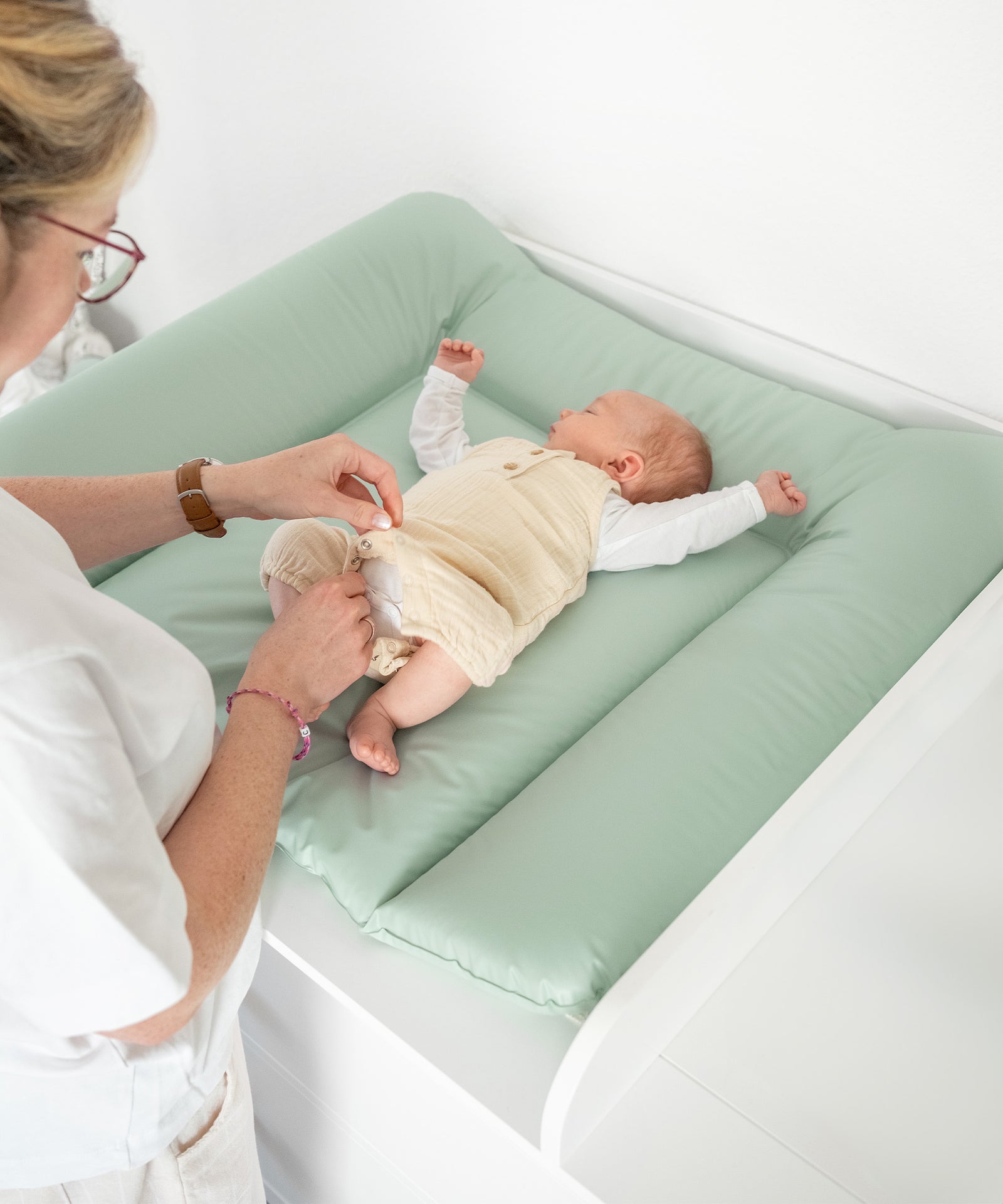 Baby wird gewickelt auf Wickelauflage abwaschbar Jade.