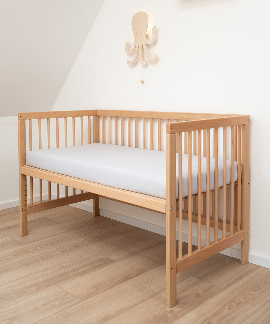 Praktisches Beistellbett*Nach Umbau kann das Babybett mit der offenen Seite direkt an das Elternbett gestellt werden.|Babybett Natur mit hoch gestellter Liegefläche und abgenommener Seite.