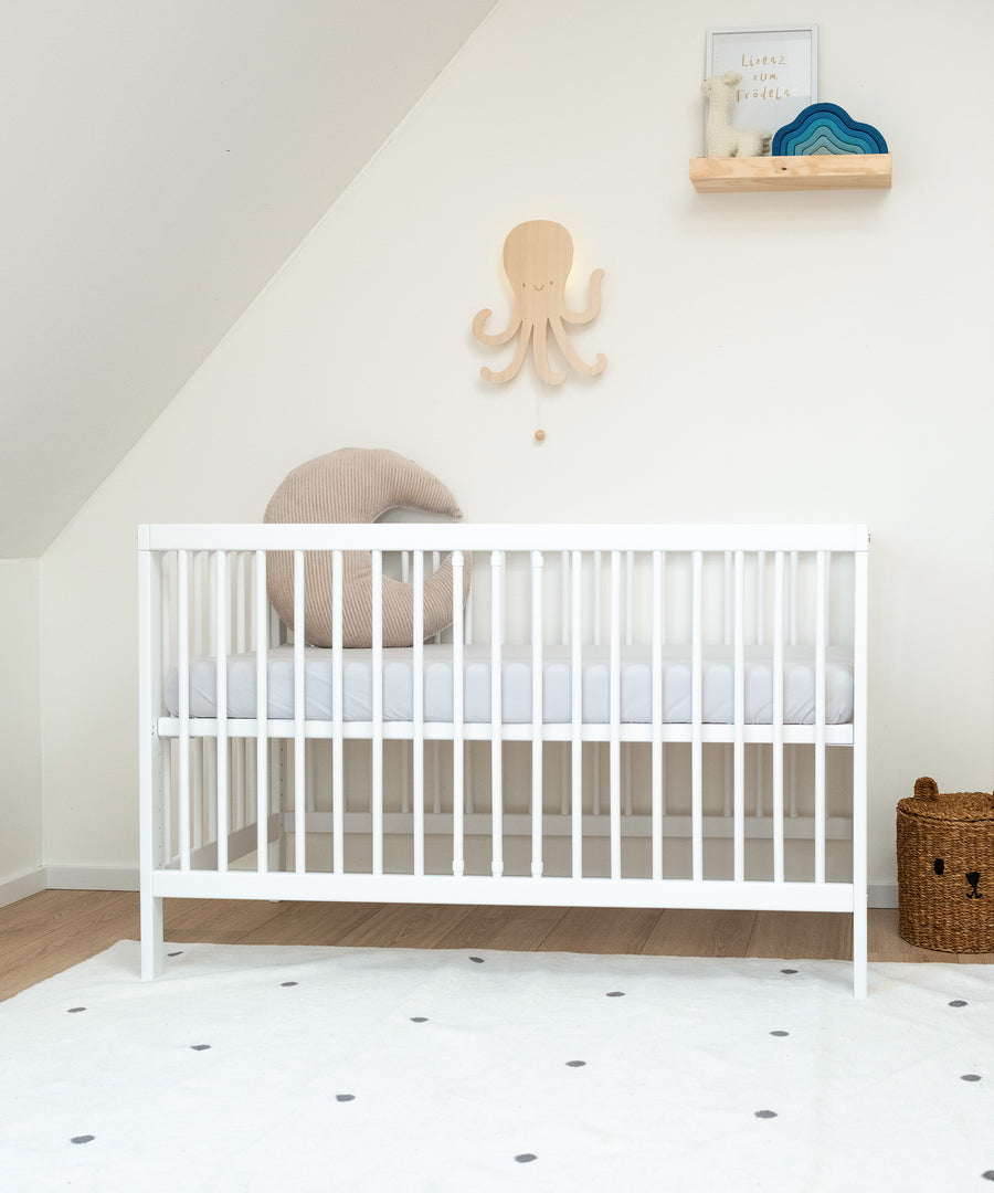 Höhenverstellbar*Die Höhe des Babybetts lässt sich individuell anpassen. So ist es flexibel und wächst mit deinem Kind mit.|Babybett weiß mit hoch gestellter Liegefläche in Kinderzimmer.