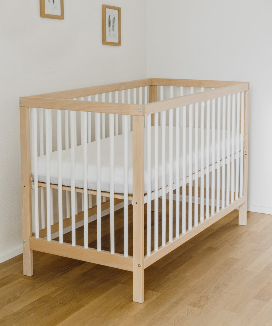 Babybett natur-weiß als Gitterbett in Kinderzimmer.