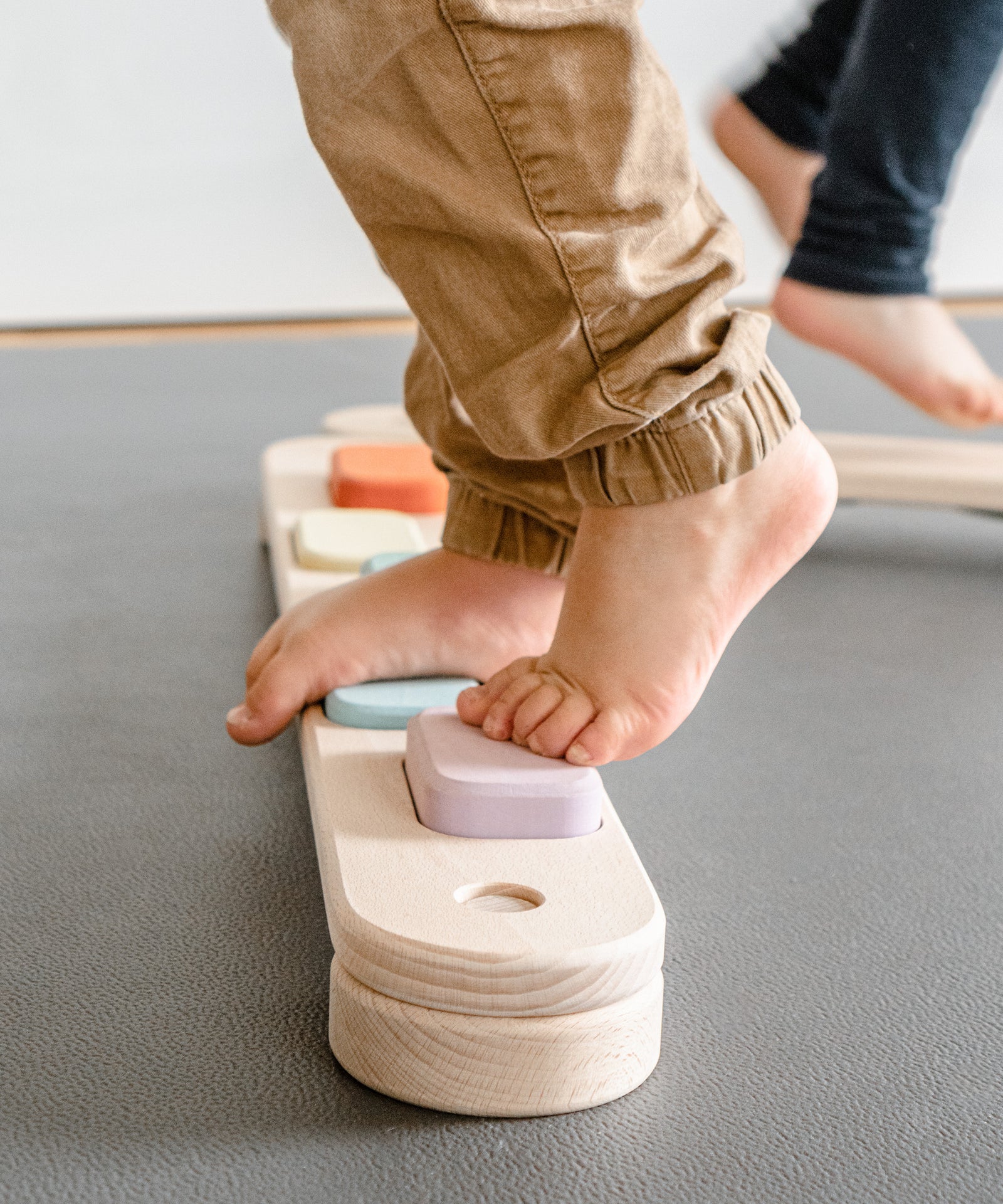Fördert gesunde Kinderfüße*Das Barfuß-Balancieren auf dem Balancierbalken trainiert optimal die kindliche Fußmuskulatur.|Nahaufnahme Kinderfüße auf Balancierbalken.