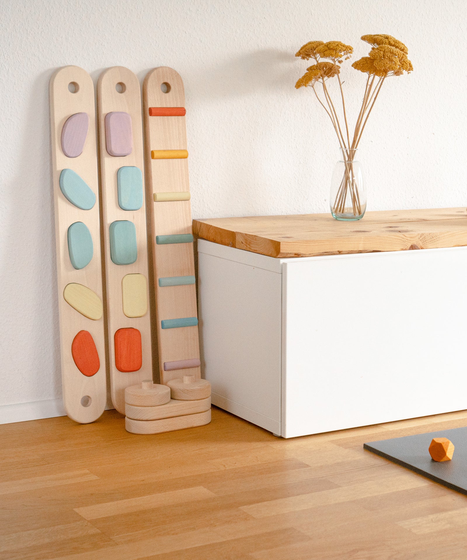 Einfache Handhabung*Durch die modulare Bauweise kann der Balancierbalken ganz einfach aufgeräumt und platzsparend verstaut werden.|Elemente des Balancierbalkens lehnen an der Wand.