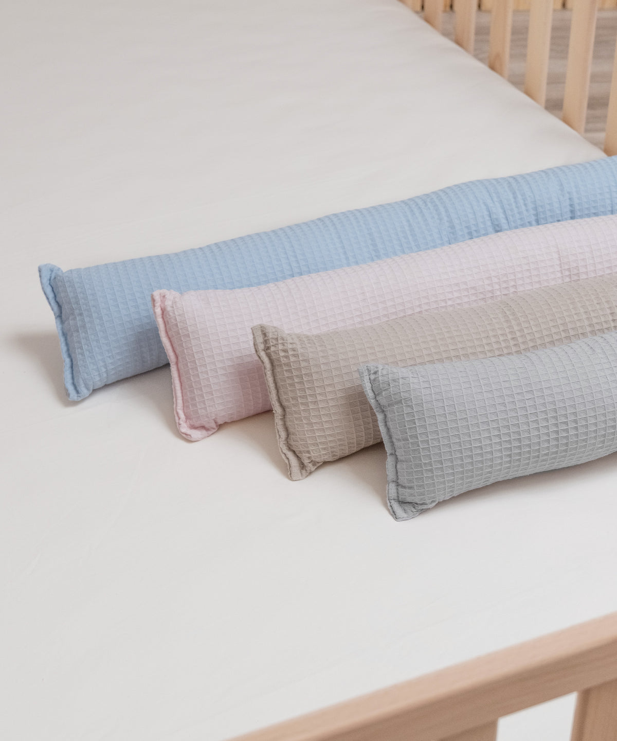 Vier Farben der Bettschlange aus Waffelpiquet liegen nebeneinander auf dem Bett.