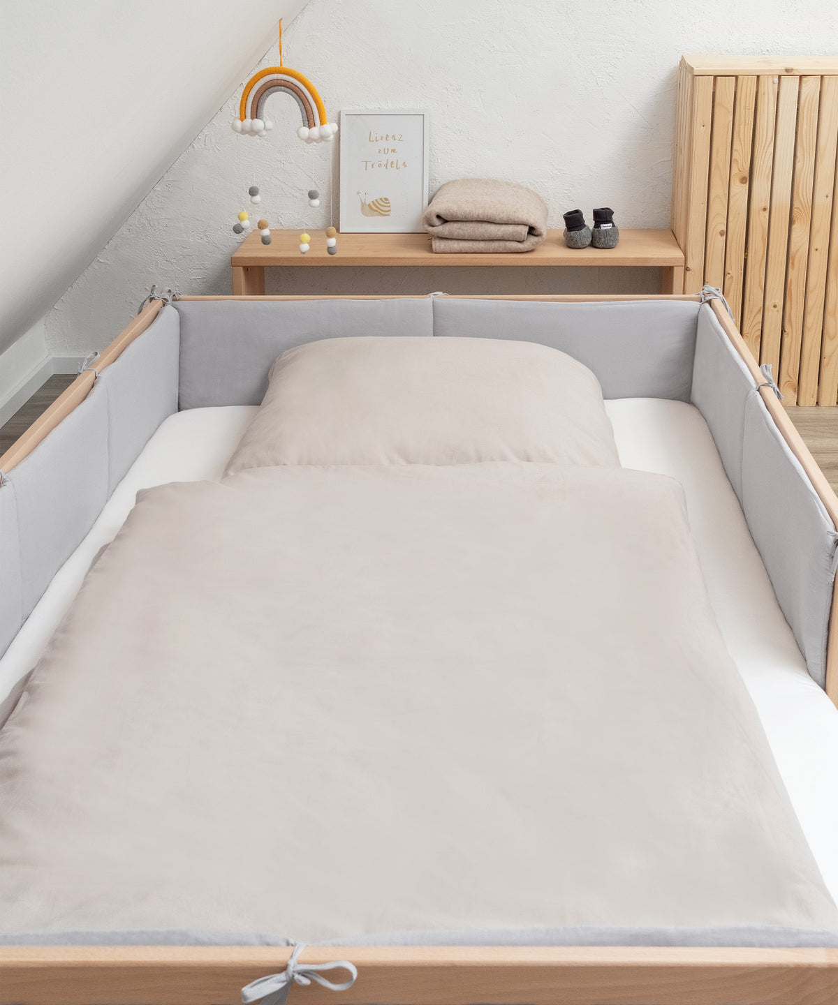 Bett der Größe 200 mal 120 cm mit Bettumrandung hellgrau und Renforcé Bettwäsche in Beige.