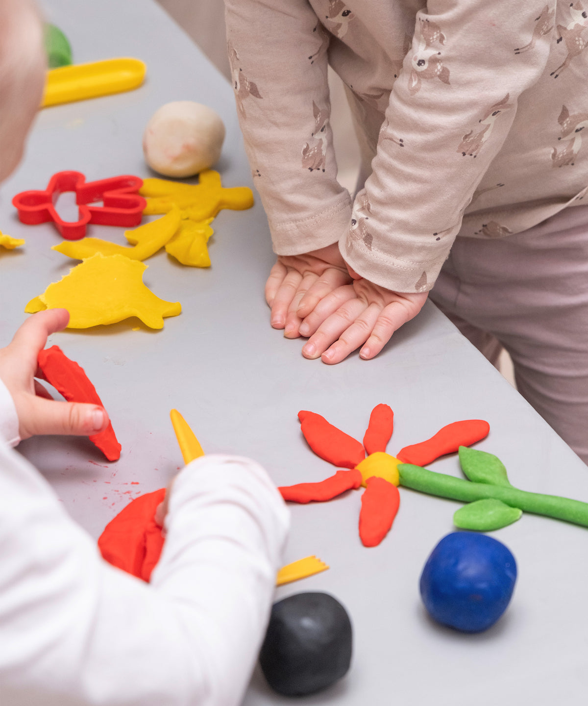 Zwei Kinder spielen mit der Bienenwachs-Knete am Tisch.