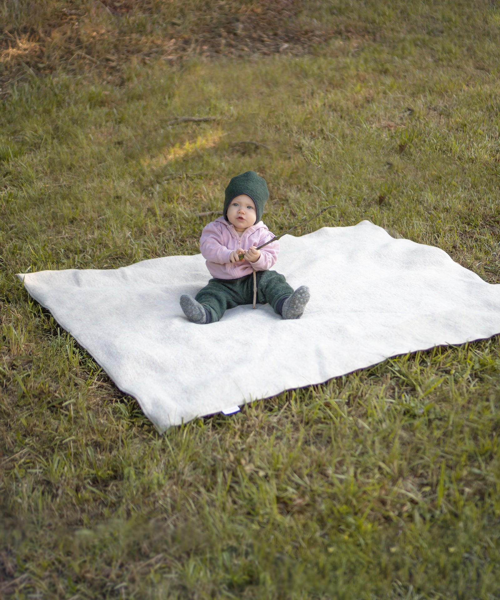 Praktisch & Pflegeleicht*Die Wolle kann Feuchtigkeit aufnehmen, ohne sich nass anzufühlen.
Das pflegeleichte Material ist von Natur aus schmutzabweisend.|Baby sitzt draußen auf einer Walkdecke.