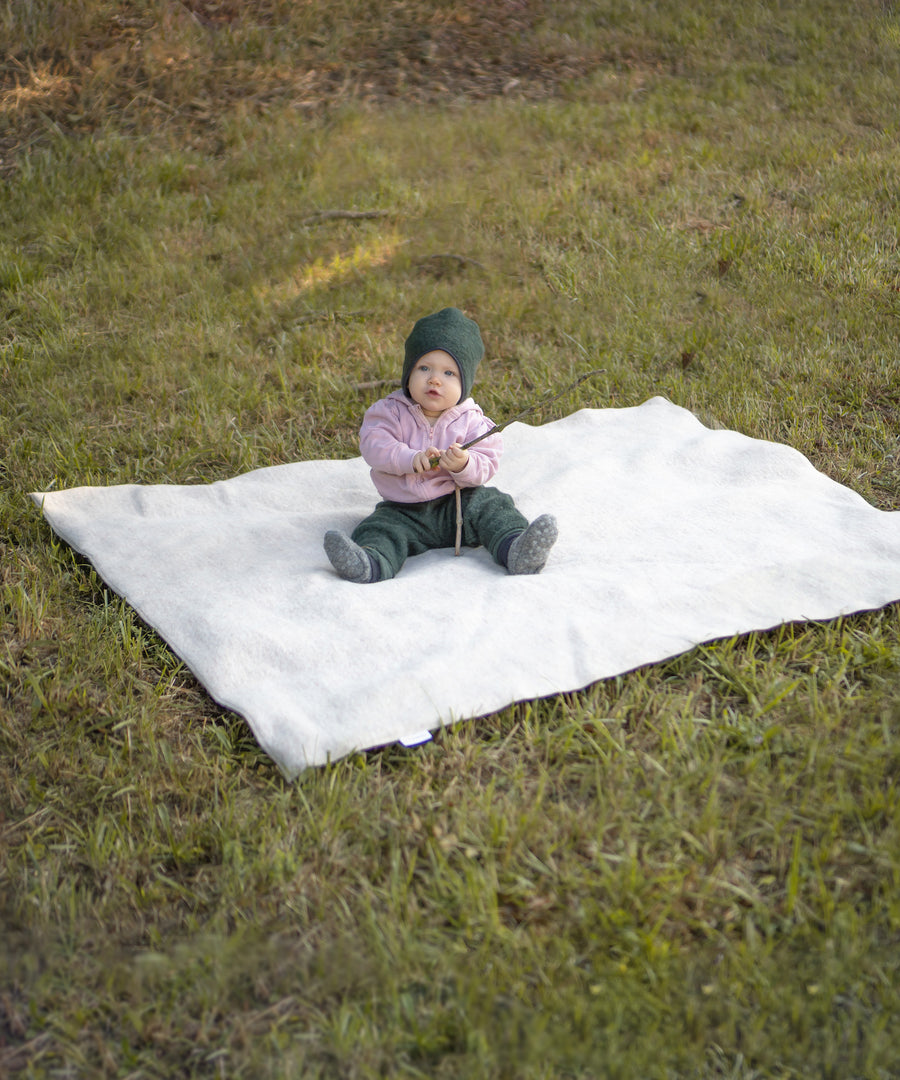 Praktisch & Pflegeleicht*Die Wolle kann Feuchtigkeit aufnehmen, ohne sich nass anzufühlen.
Das pflegeleichte Material ist von Natur aus schmutzabweisend.|Baby sitzt draußen auf einer Walkdecke.