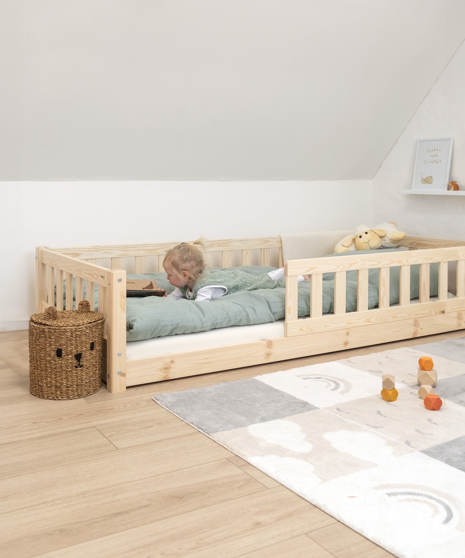 Mädchen liegt in Bodenbett Kiefer und schaut Buch an.