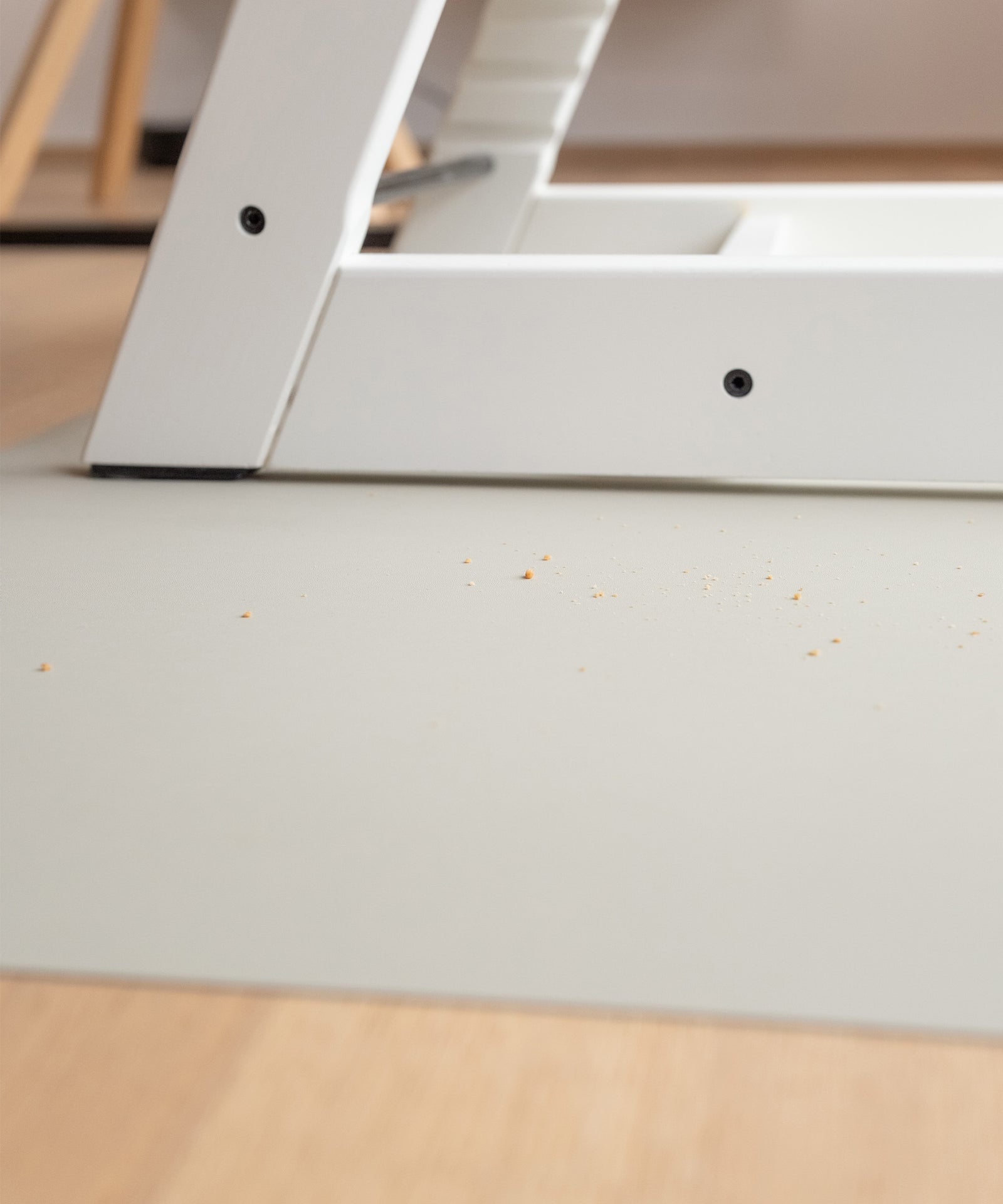 Hochstuhl steht auf rutschfester Bodenmatte, Krümel liegen auf der Matte.
