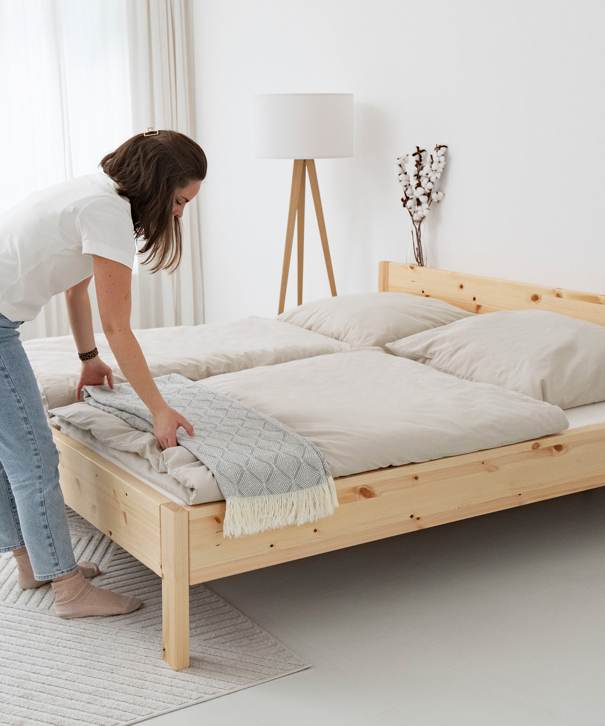 Frau legt Decke auf Doppelbett Kiefer Natur Standardhöhe.