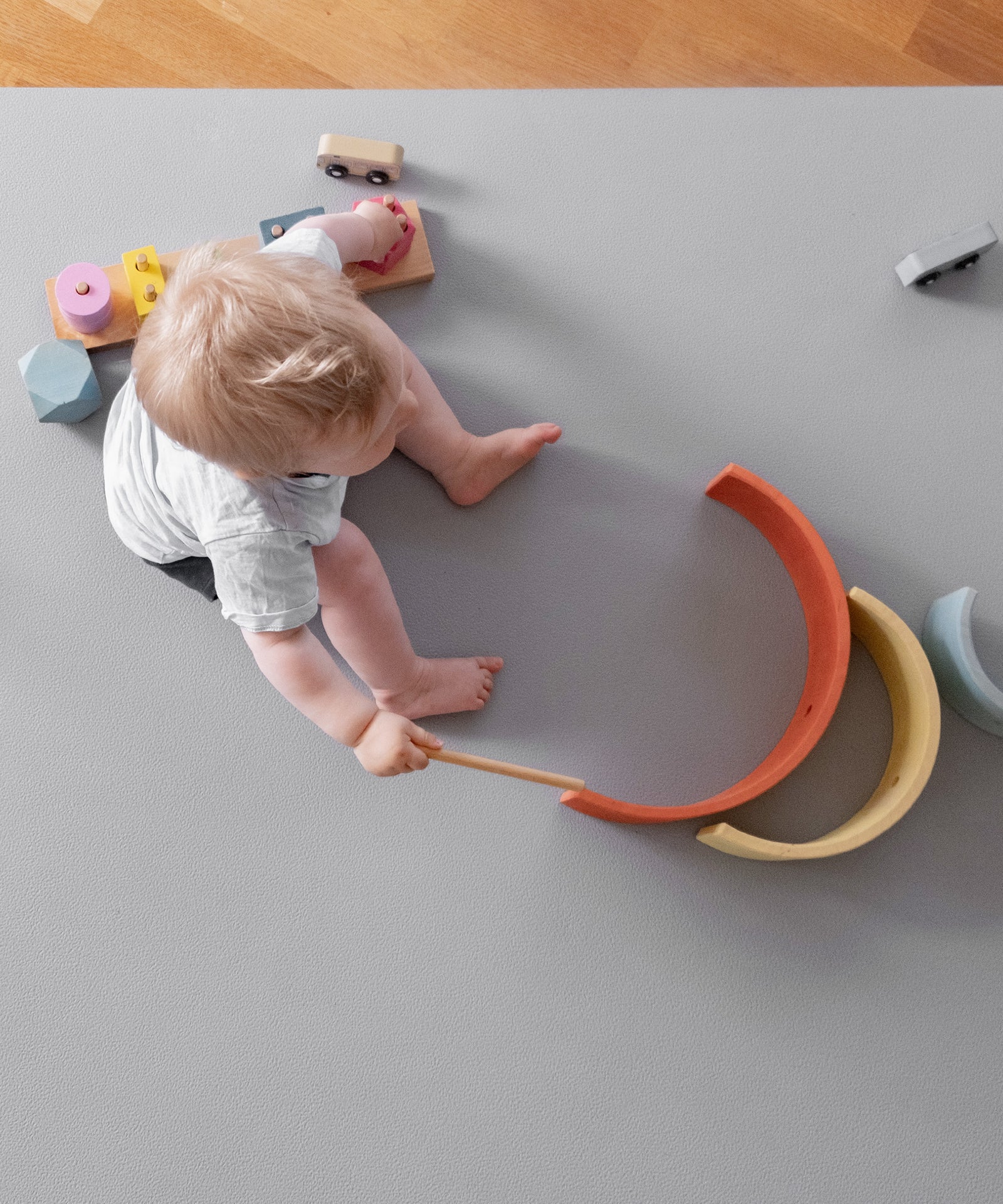 Kind mit Holzregenbogen auf Krabbelmatte Pro Hellgrau.