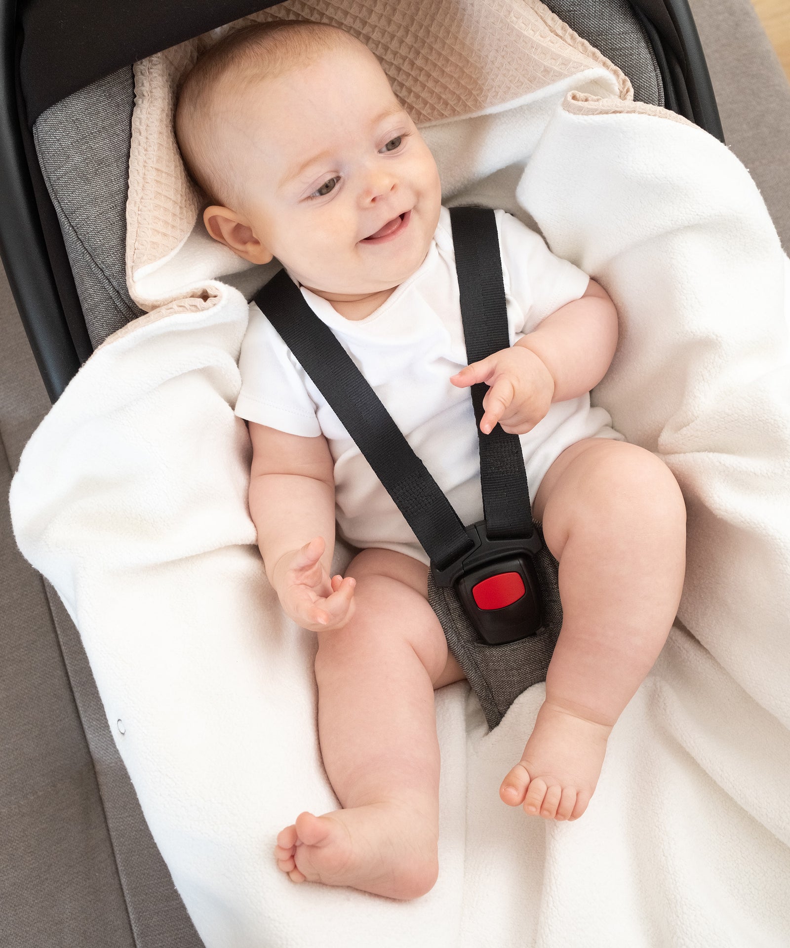 Für 3-Punkt-Gurtsystem*Die Einschlagdecke ist mit fünf Schlitzen ausgestattet und kompatibel mit dem 3-Punkt-Gurtsystem gängiger Babyschalen.|Baby mit Einschlagdecke angeschnallt in Babyschale.