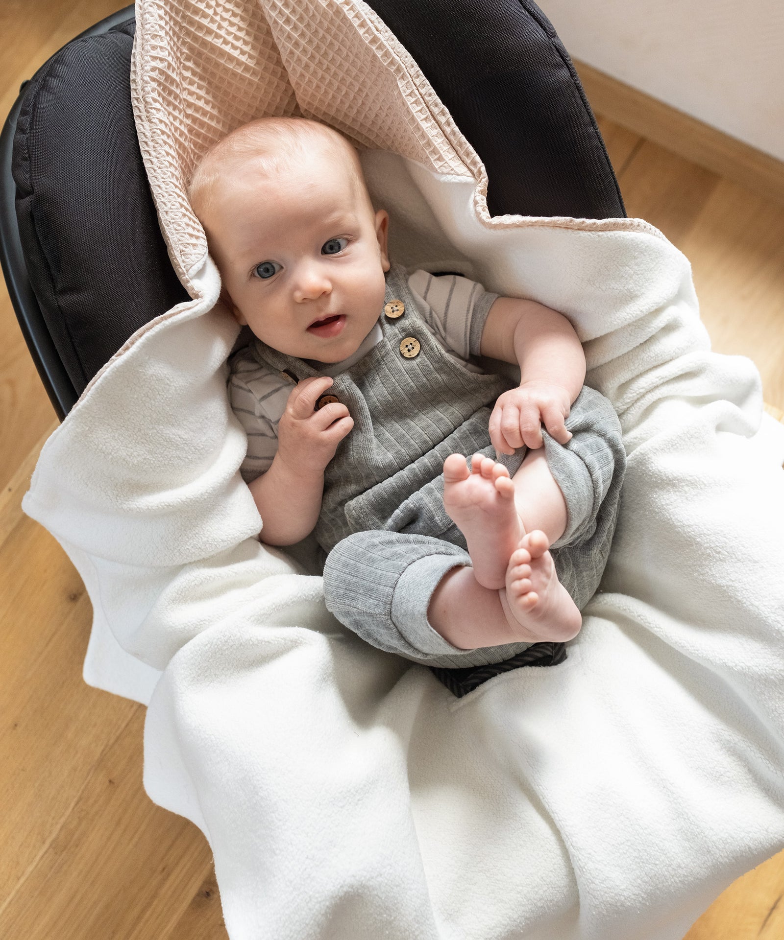 Weich & hautfreundlich*Ideal für empfindliche Babyhaut: Beide Seiten der Decke bestehen aus hochwertiger, nachhaltiger Bio-Baumwolle.|Baby mit Einschlagdecke in Babyschale, kuschelig weiche Teddyseite ist innen.