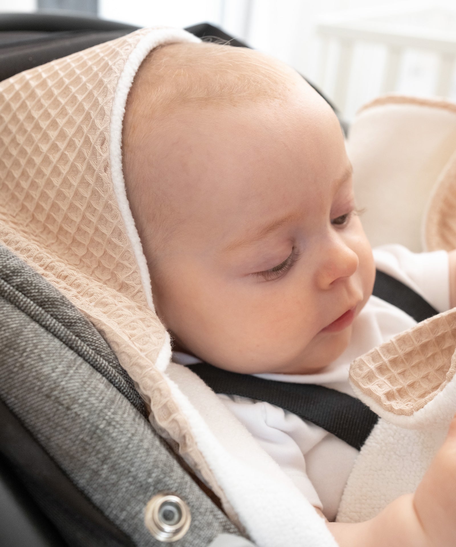 Baby mit Einschlagdecke Kapuze auf dem Köpfchen, Decke aus hautfreundlicher Bio-Baumwolle.