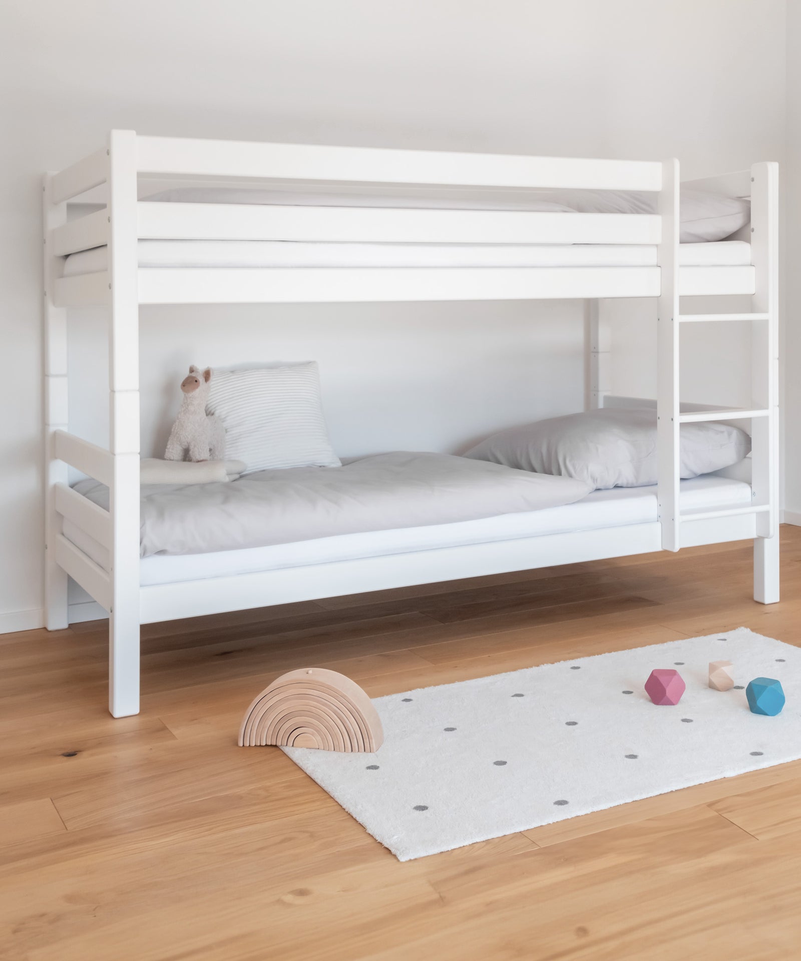 Raumwunder*Das Etagenbett bietet auf wenig Raum genügend Platz für zwei Schlafplätze und ist daher ideal für kleine Kinderzimmer.|Mittelhohes Etagenbett in Weiß mit rechts montierter Leiter.