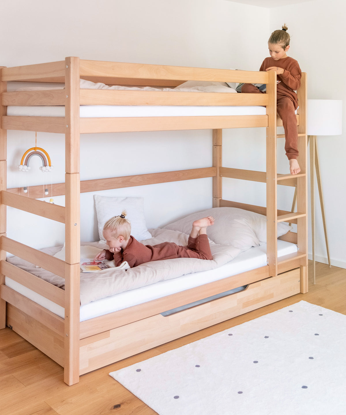 Zwei Geschwisterkinder sind auf dem Etagenbett, schauen Bücher an, ein Kind oben, ein Kind unten.