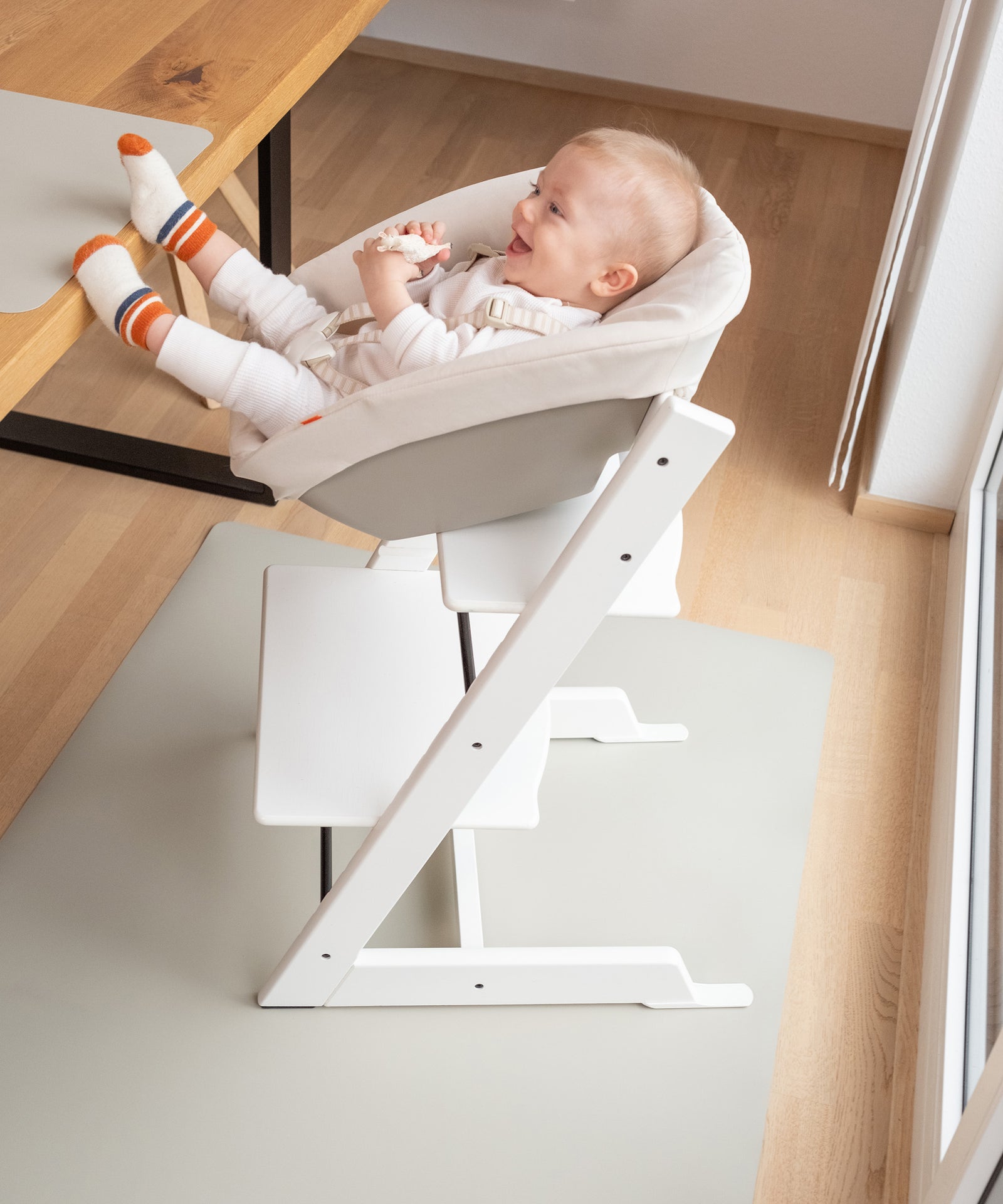 Baby in Hochstuhl auf Bodenmatte, Fußbodenschutz für den Esstisch.