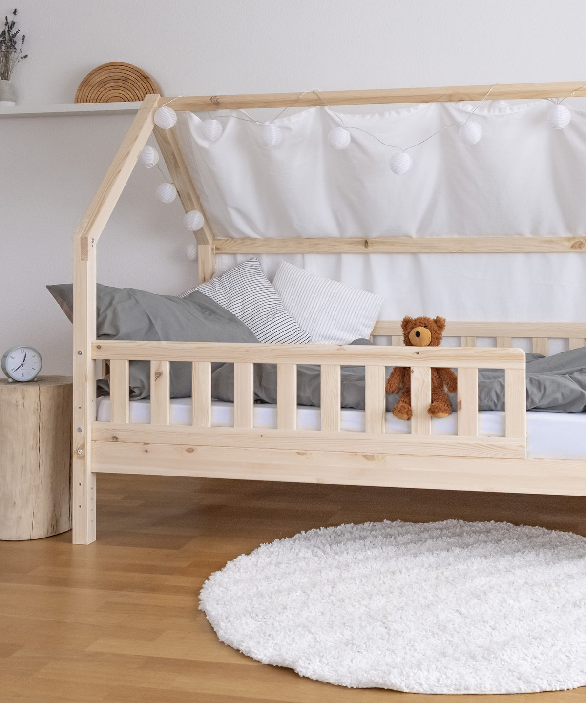 Hausbett Kiefer mit Betthimmel und Bettwäsche steht in Kinderzimmer.