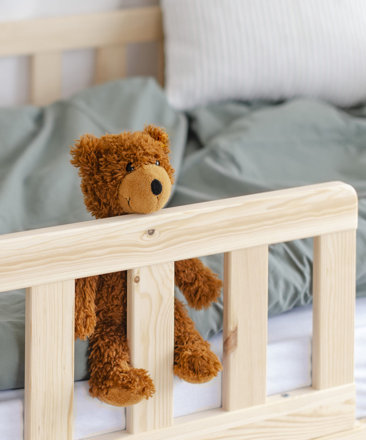 Nahaufnahme Rausfallschutz mit Teddybär, der darüber aus dem Bett schaut.