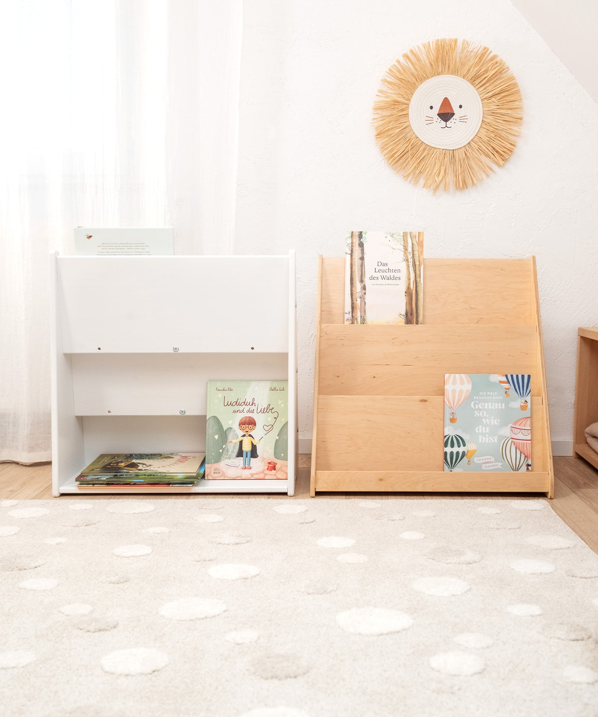 Das Bild zeigt zwei Bücherregale in einem Kinderzimmer. Das linke Bücherregal in weiß lackiert präsentiert die Rückansicht, bei der zusätzlich Bücher auf der Rückseite verstaut werden können, um mehr Stauraum zu schaffen. Das rechte Regal ist transparent lackiert und zeigt die Bücher frontal an.