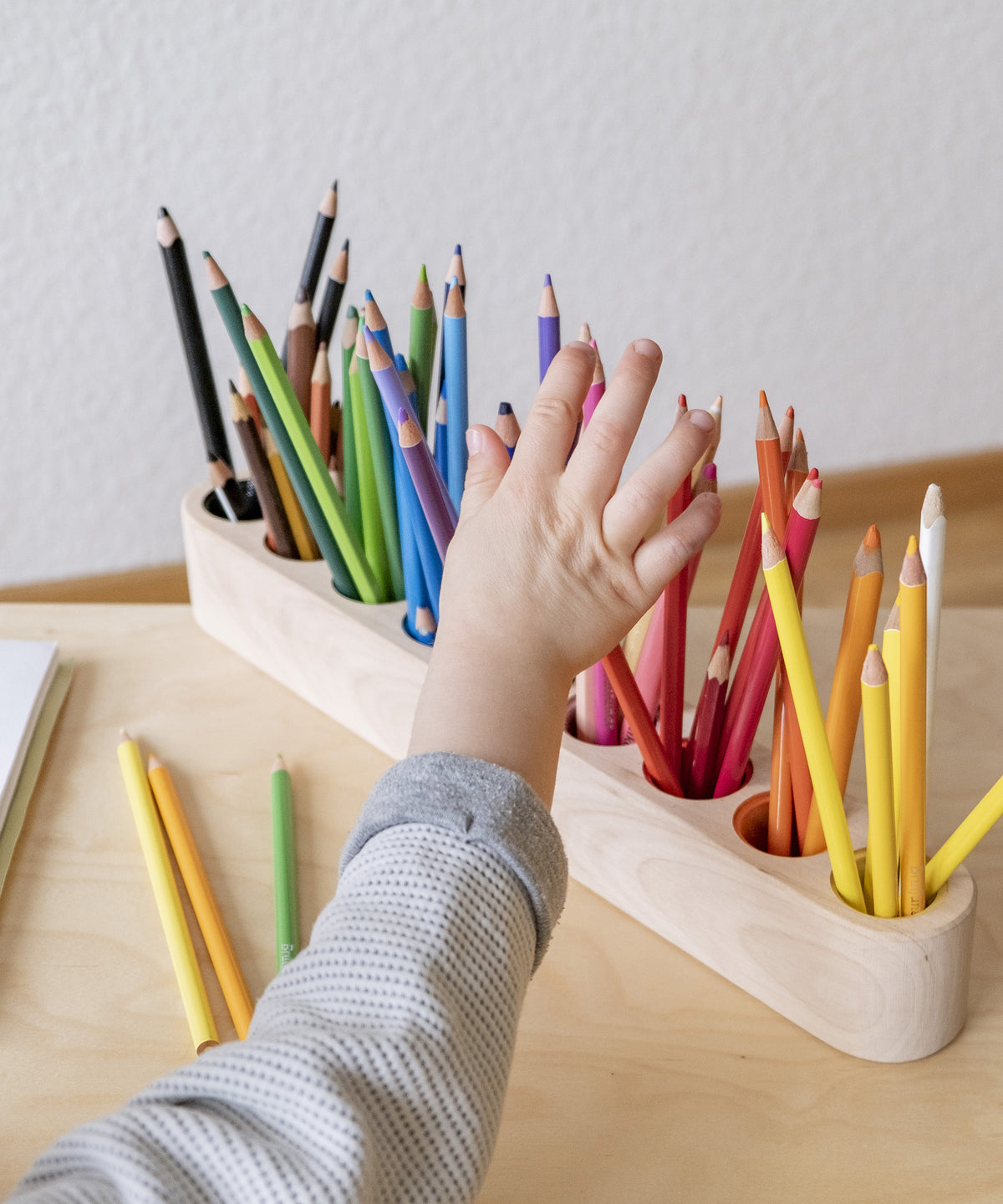 Kind greift nach Stift in Kinder Stiftehalter.