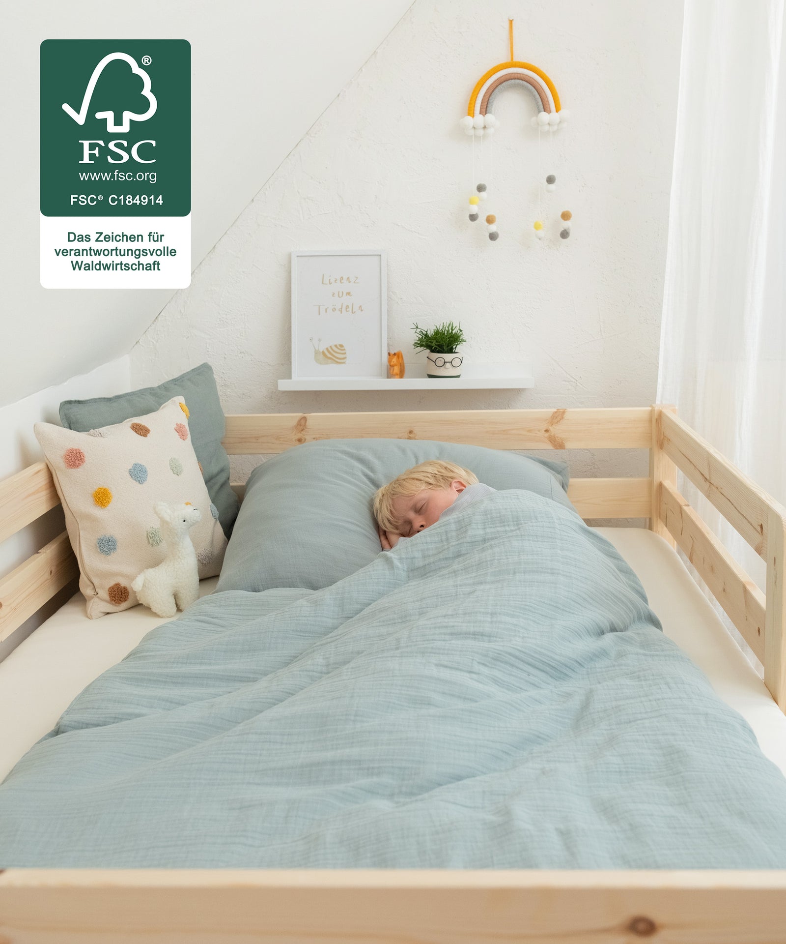 Einfach gemütlich*Das Kinderbett bietet genug Platz zum Kuscheln, Spielen, Schlafen und Gute-Nacht-Geschichten lesen.|Kind liegt in Kinderbett und schläft, Kinderbett FSC zertifiziert.