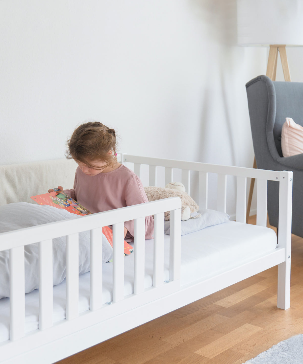 Kinderbett Buche weiß mit Bettkasten und links montiertem Rausfallschutz.