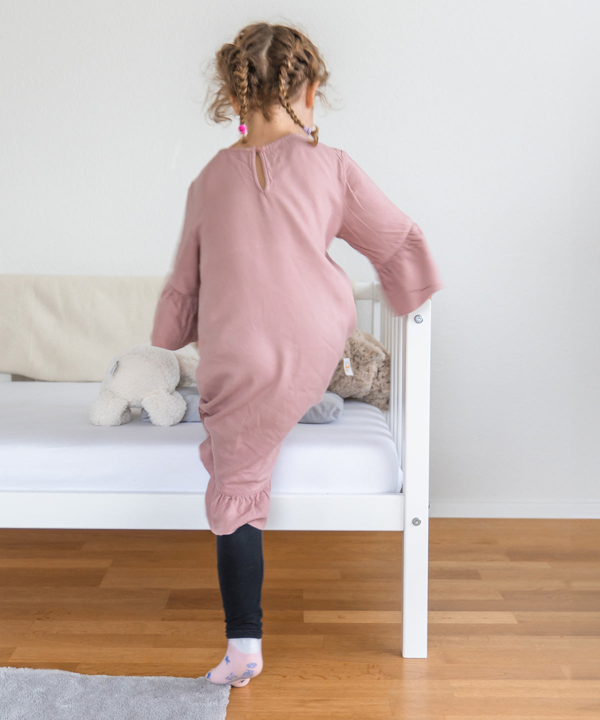 Mädchen steigt auf Kinderbett Buche weiß. 