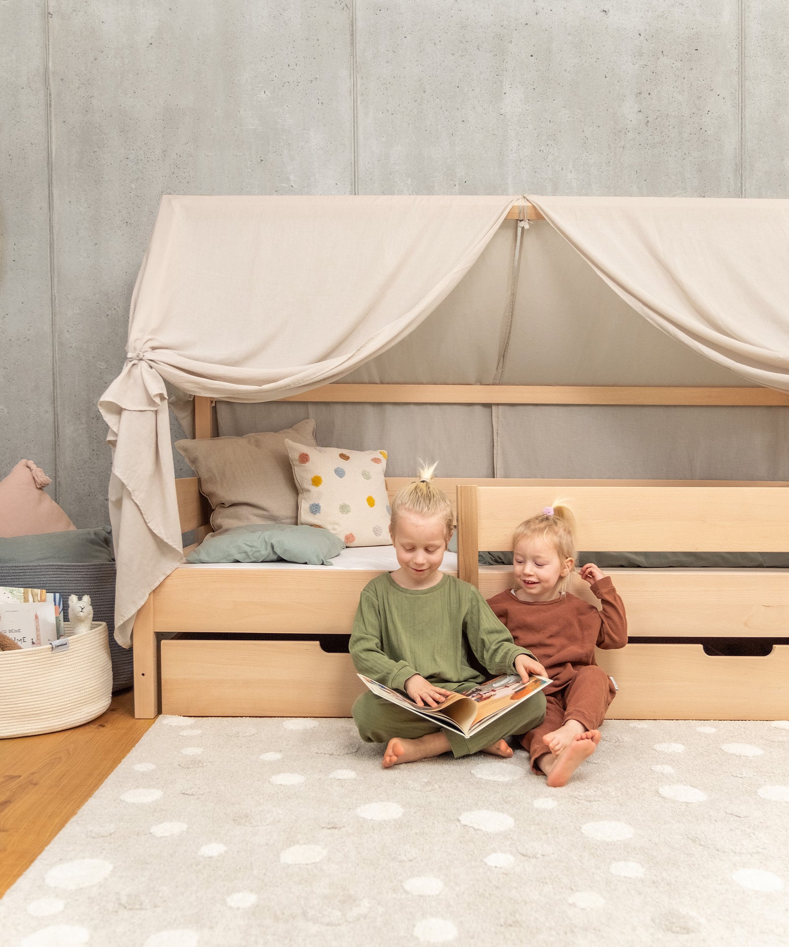 2 Größen & 2 Farben*Das Bett ist erhältlich in Weiß und Natur in den Größen 90 × 200 cm und 120×200 cm - genug Platz zum gemeinsamen Kuscheln.|Zwei Kinder lesen zusammen vor einem Hausbett.