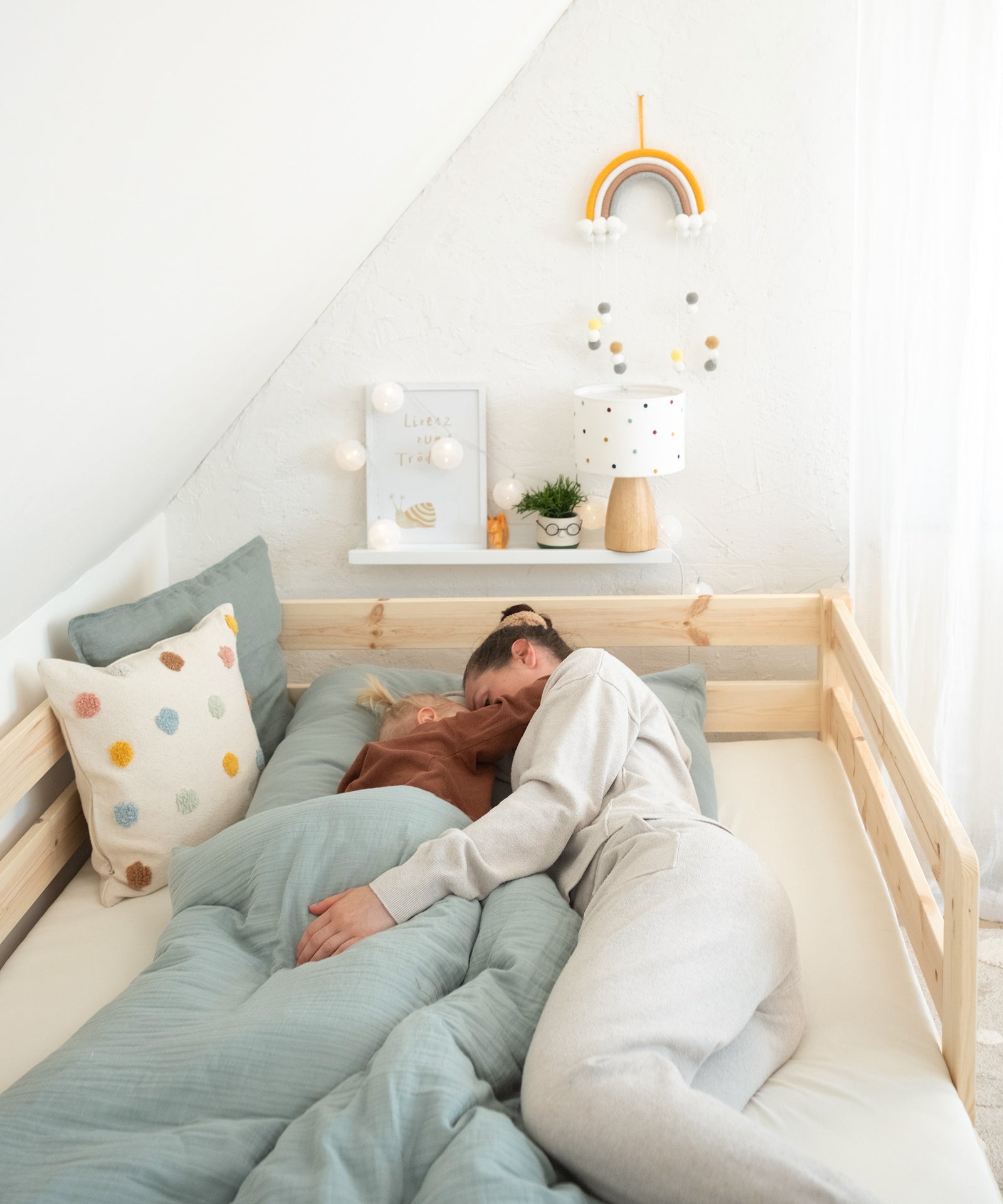 Ideal zur Einschlafbegleitung*Das Kinderbett ist bis 100 kg belastbar - du kannst dich für die Einschlafbegleitung also unbesorgt zu deinem Kind legen.|Kind und Mama liegen zum Einschlafen im Kinderbett.