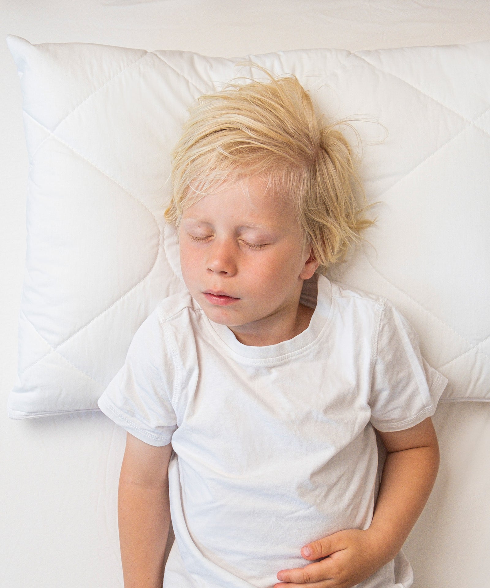 Für Rückenschläfer*Durch die drei herausnehmbaren Innenkissen kann die Kissenhöhe individuell an die Schlafposition von Rückenschläfern angepasst werden.|Junge schläft auf dem Rücken auf höhenverstellbarem Kissen.