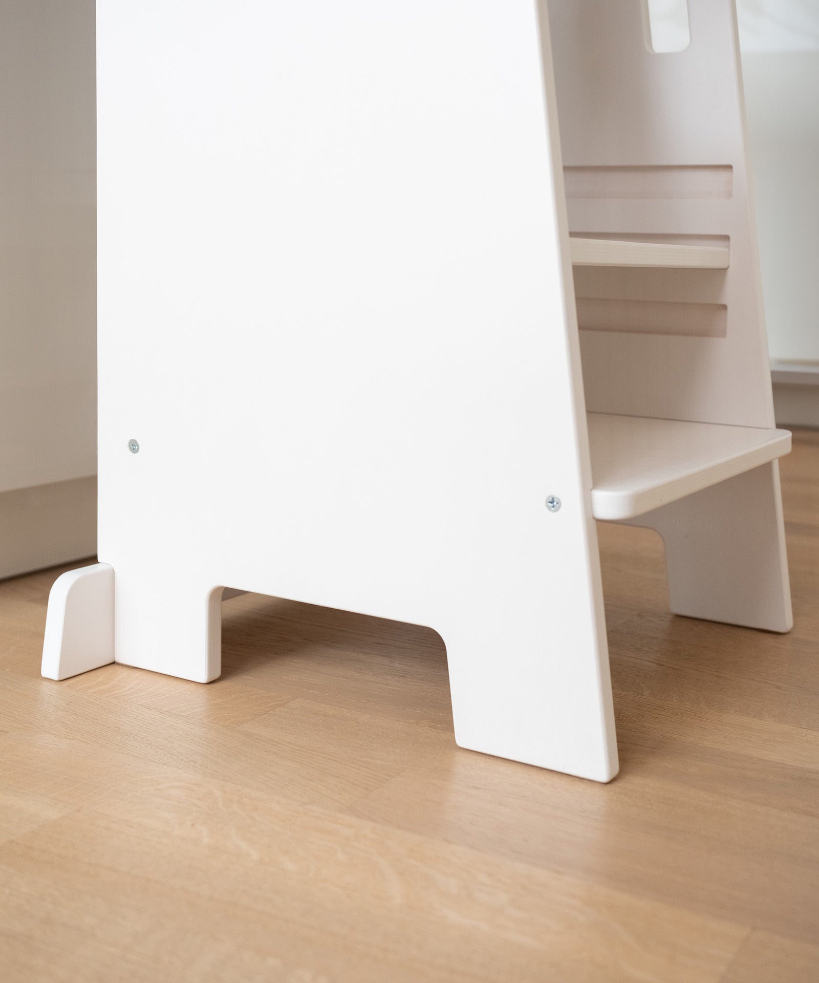 Hochwertig & standfest*Der Lernturm besteht aus hochwertigem Birkenschichtholz.
Die Fußleiste sorgt für einen dauerhaft stabilen Stand.|Nahaufnahme des unteren Bereichs des weißen Lernturms auf einem Holzboden.