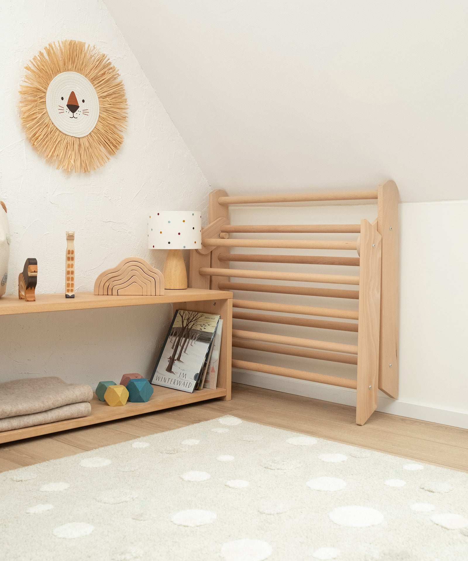 Zusammenklappbar*Das Kletterdreieck kann mit wenigen Handgriffen platzsparend
zusammengeklappt werden.|Das Kletterdreieck steht zusammengeklappt neben einem Regal in der Ecke.