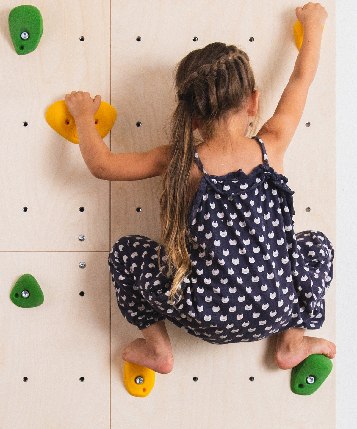 Mädchen klettert an Kletterwand für's Kinderzimmer.