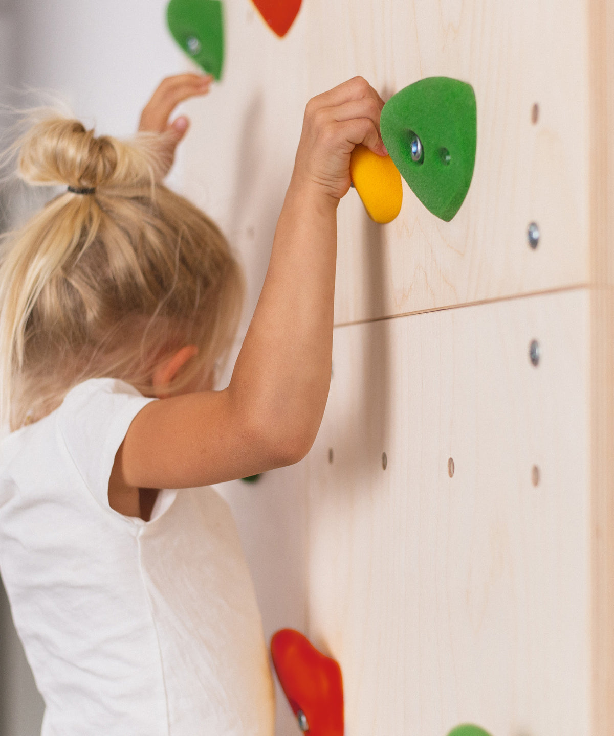 Mädchen klettert an Indoor Kletterwand für Kinder.