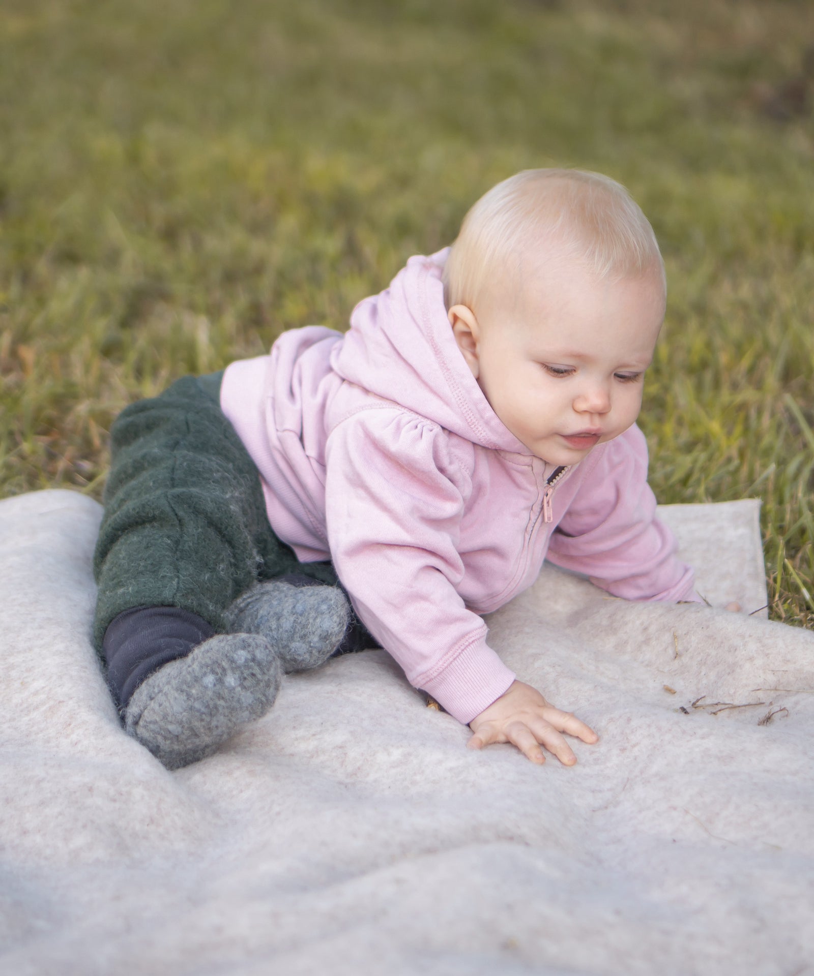 Baby sitzt auf einer Walkdecke.