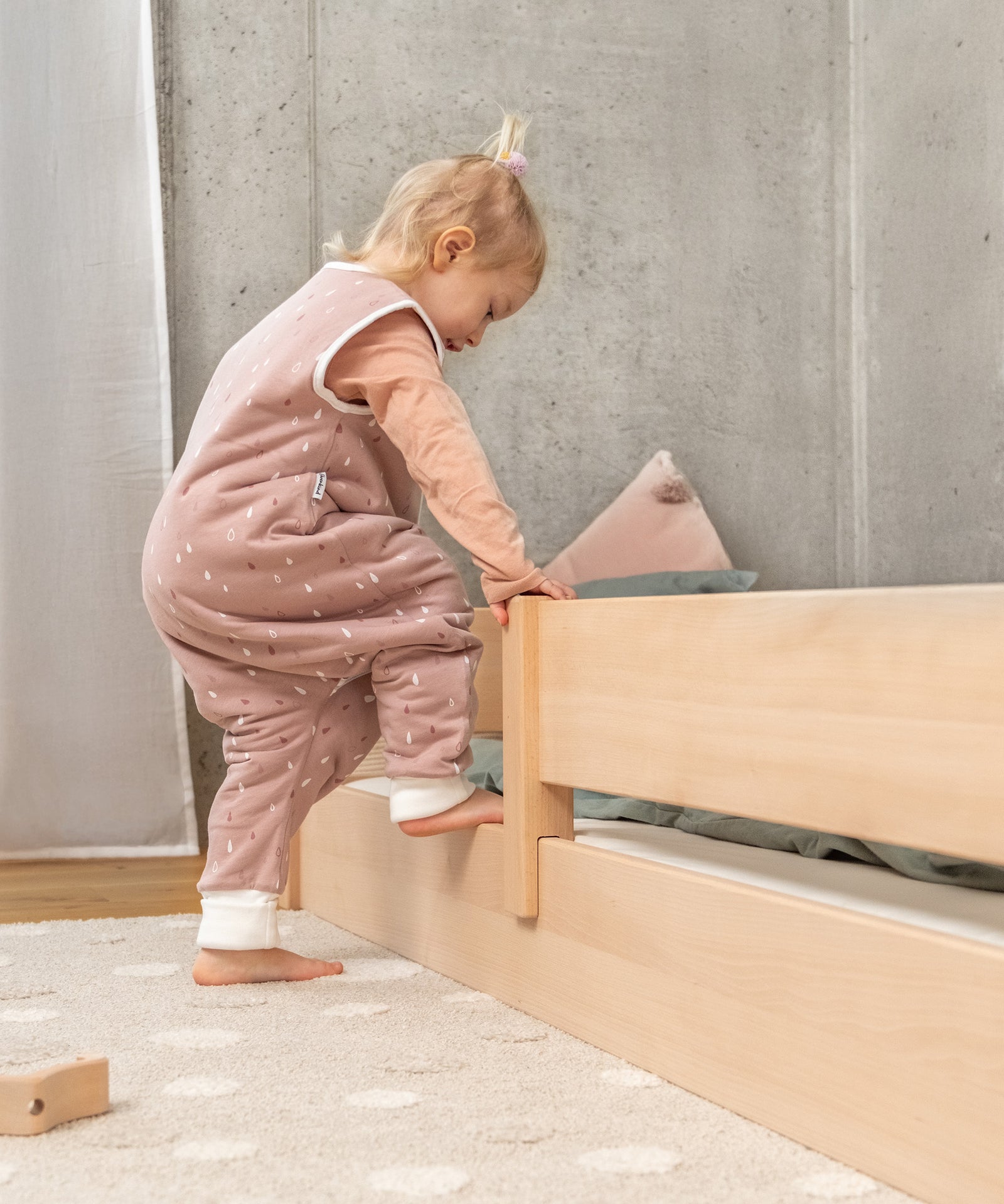 Bodennaher Einstieg*Dein Kind kann selbstständig und sicher ein- und aussteigen. Trotz bodennaher Liegefläche wird die Matratze optimal belüftet.|Mädchen steigt in Bodenbett, Einstieg ist bodennah.