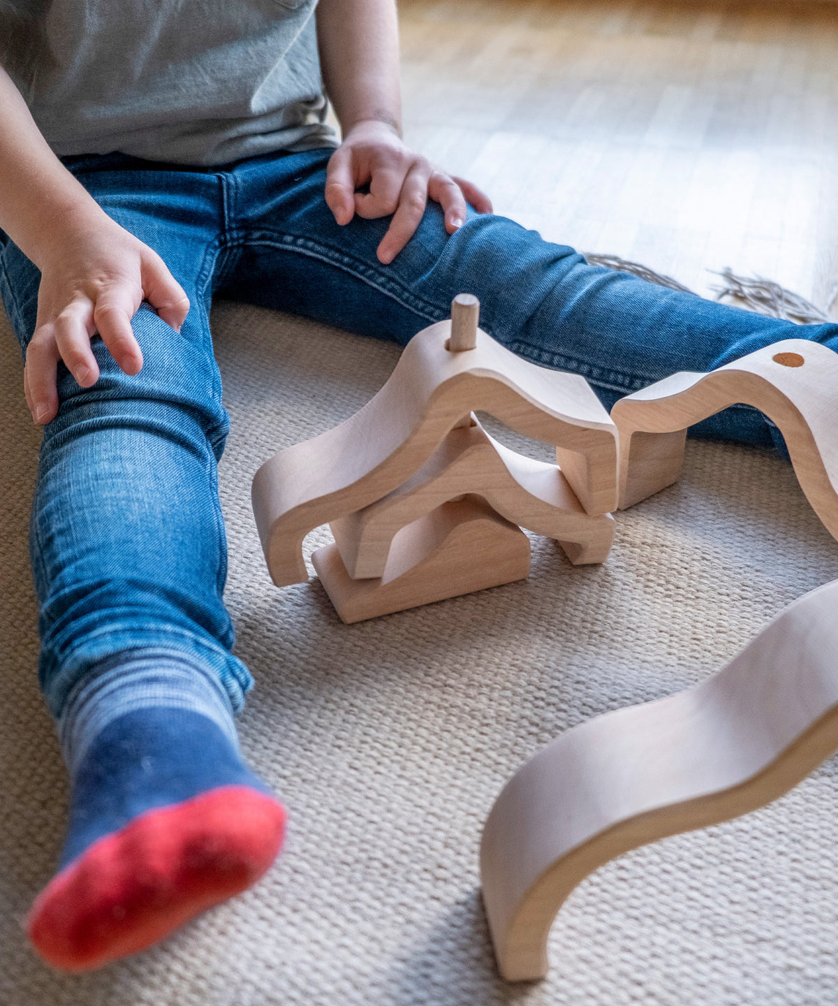 Kind spielt mit Montessori Holzspielzeug Wolke natur.