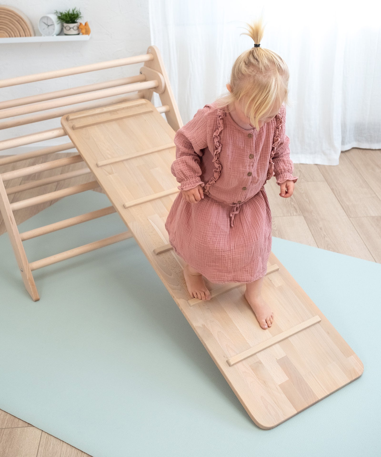 Multifunktional*Das Rutschbrett hat auf der Rückseite eingelassene Sprossen, mit denen dein Kind es auch als Hühnerleiter verwenden kann.|Kind läuft auf der Hühnerleiter herunter.