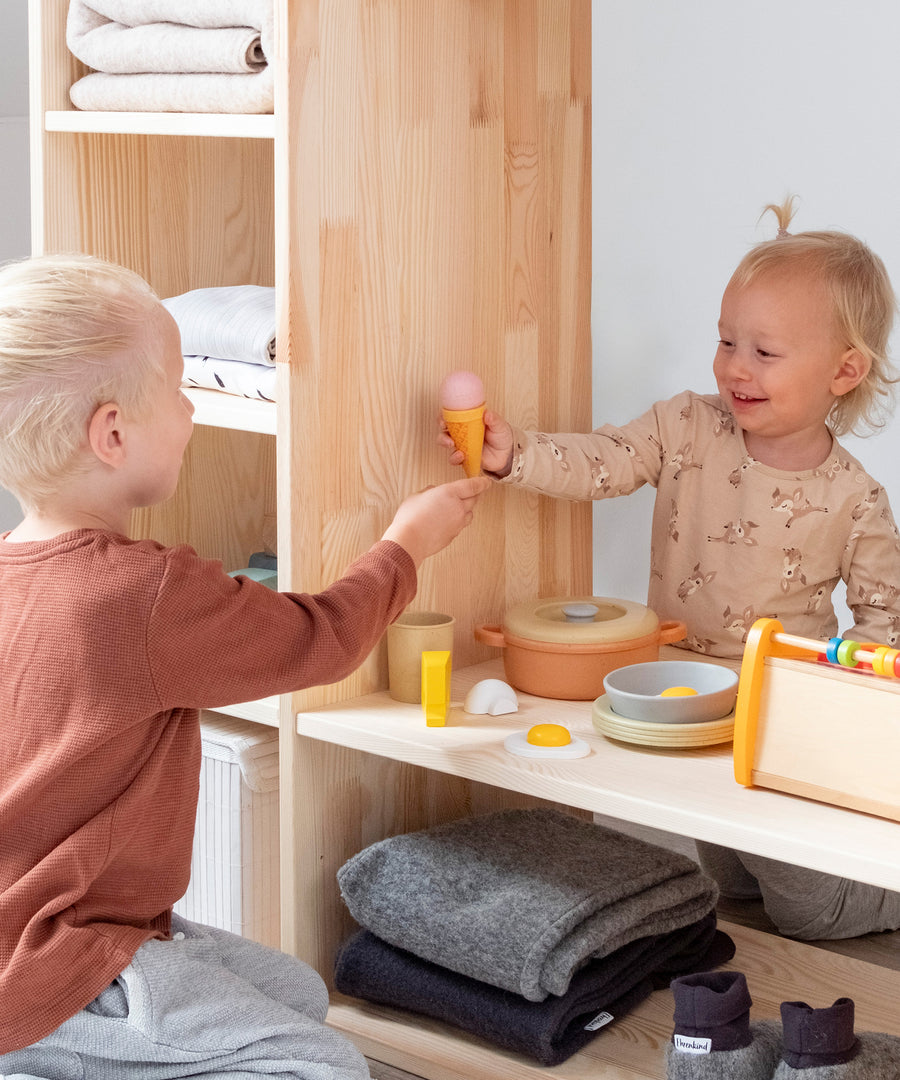 Kreatives Freispiel*Als Raumteiler positioniert lädt der Montessori Kleiderschrank dein Kind zum kreativen Spiel ein.|Zwei Kinder spielen Kaufladen am Montessori Kleiderschrank.