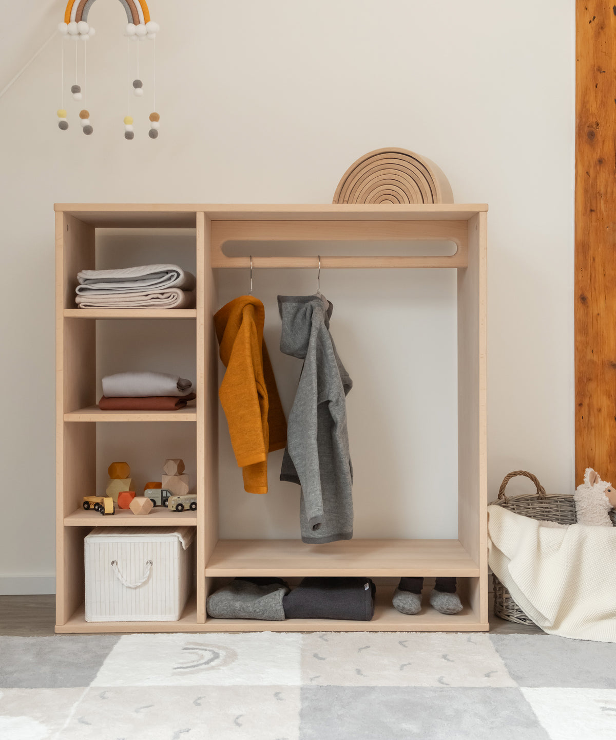 Frontansicht Montessori Kleiderschrank Buche mit Kleidung und Accessoires darin.