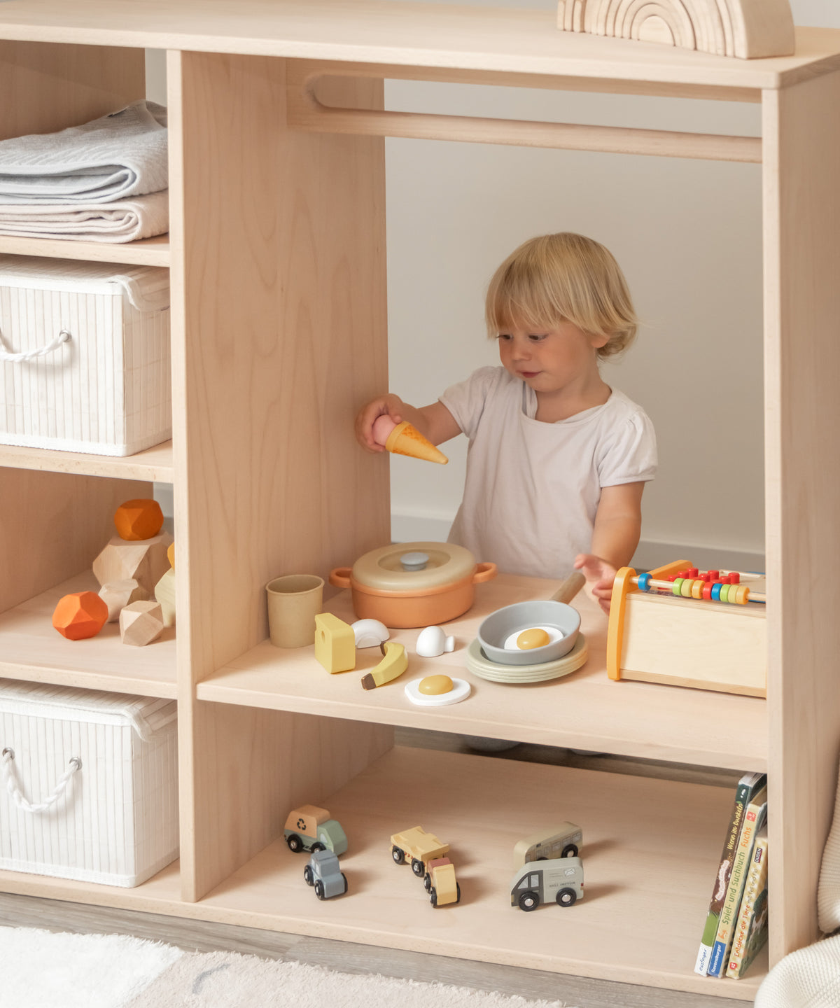 Mädchen spielt Kaufladen am Montessori Kleiderschrank.