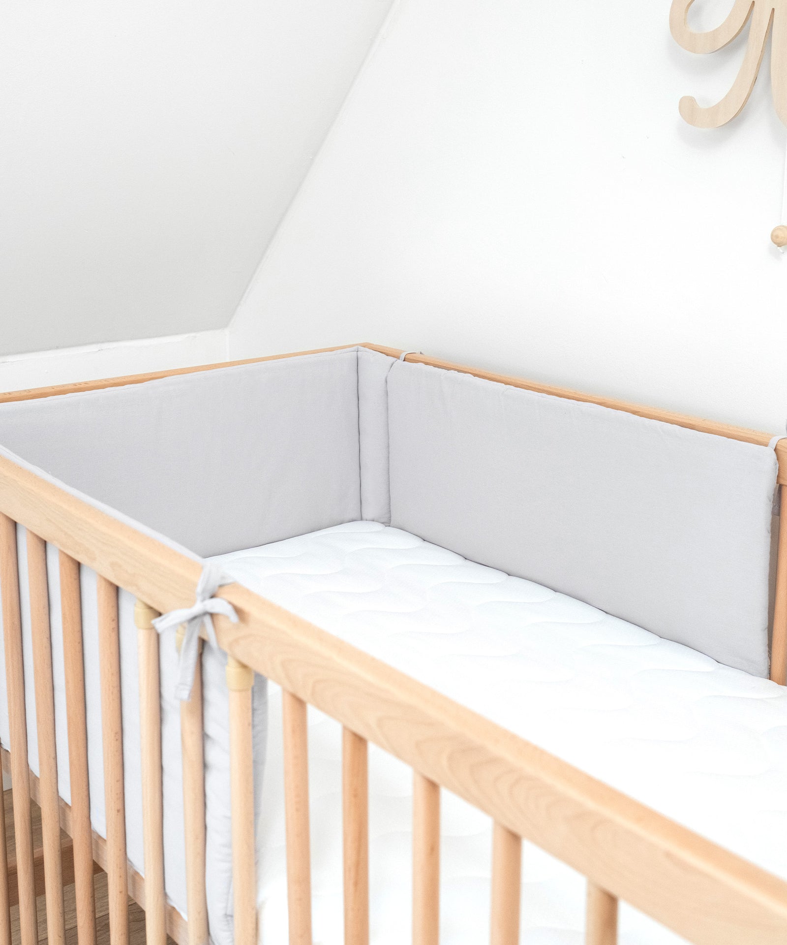 Individuell einsetzbar*Die Bettumrandung ist die ideale Ergänzung für unsere Babybetten in den Größen 140 × 70 cm und 120 × 60 cm.|Nahaufnahme Bettumrandung Hellgrau in Gitterbett.