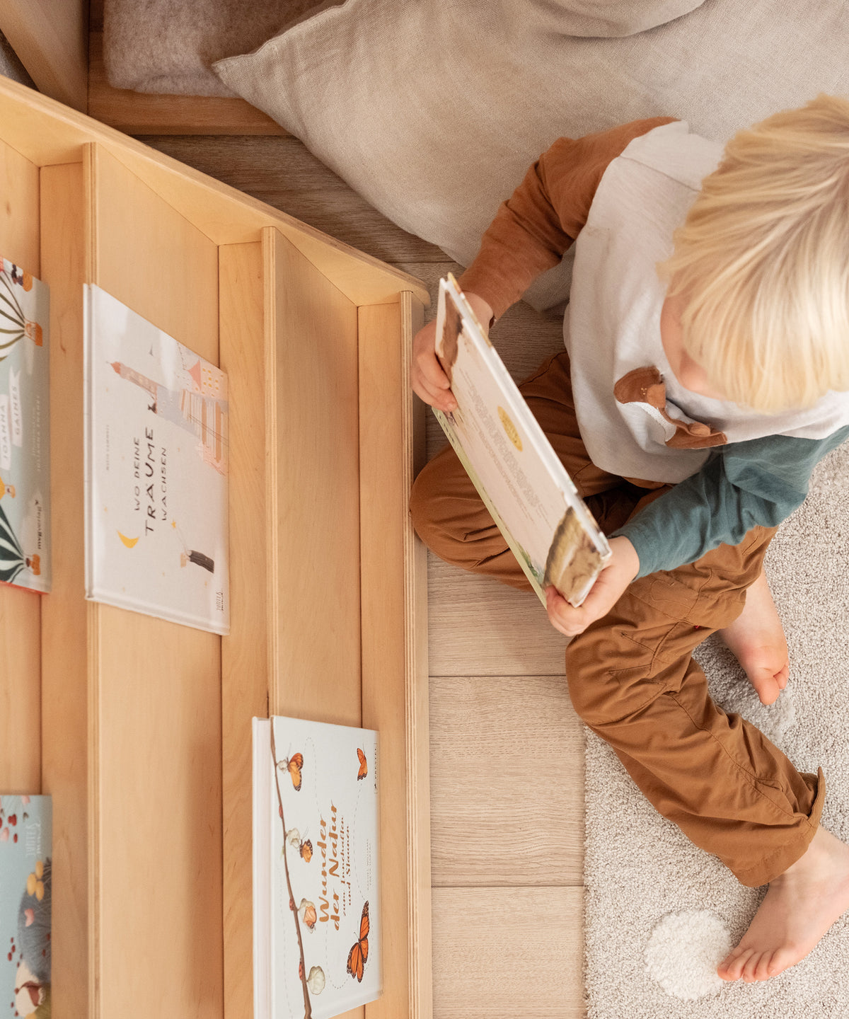Ein Kind sitzt vor dem Bücherregal und nimmt sich ein Buch heraus.