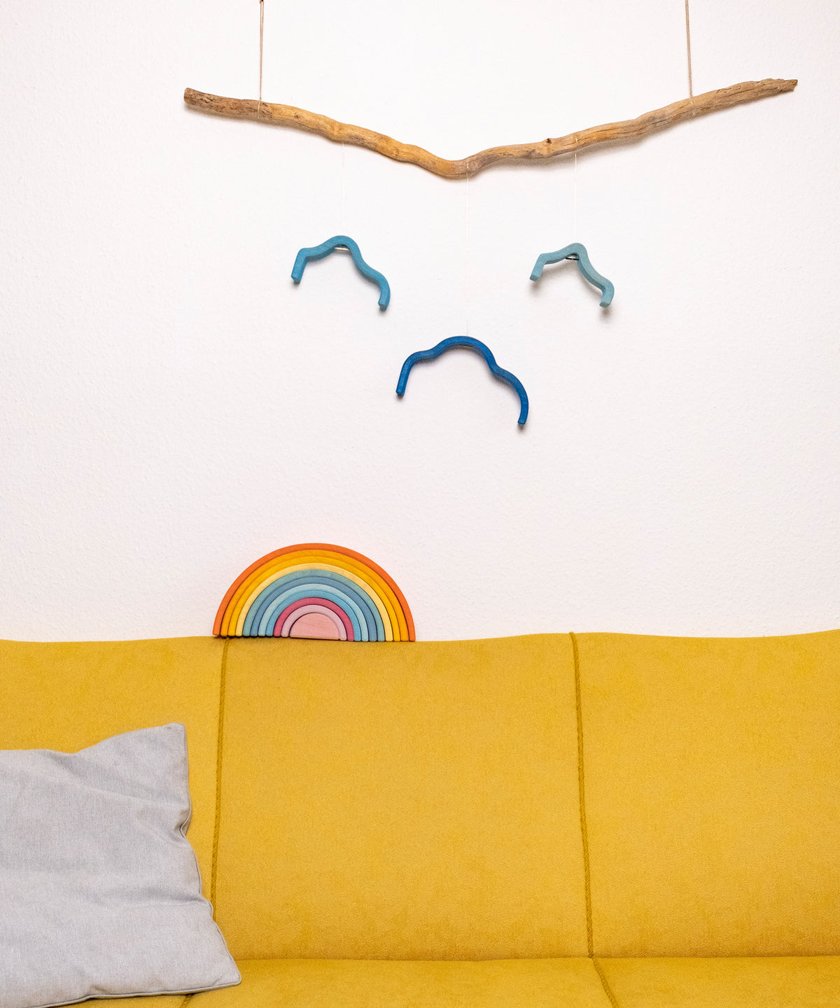 Regenbogen und Wolke auf gelbem Sofa.