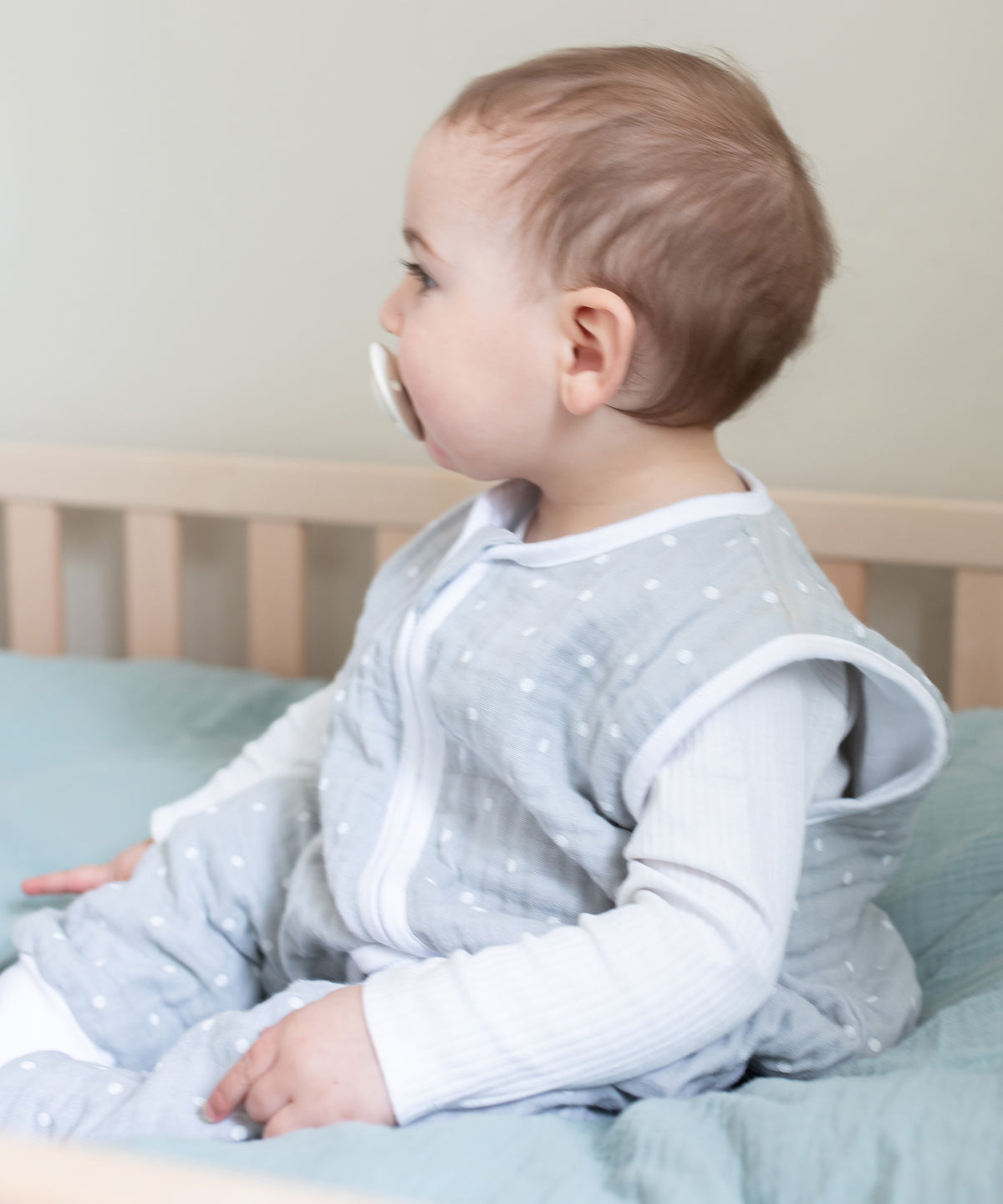 Baby mit Sommerschlafsack aus Musselin in Farbe Grau.